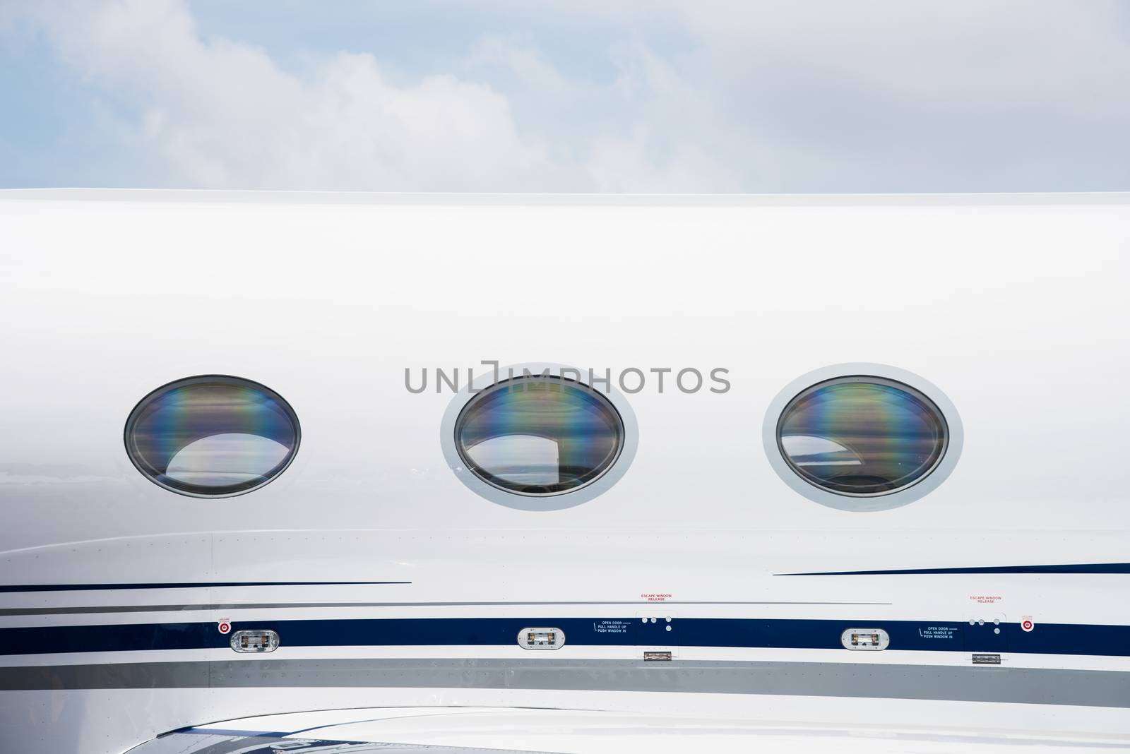 Windows and fuselage detail of white business jet aircraft.