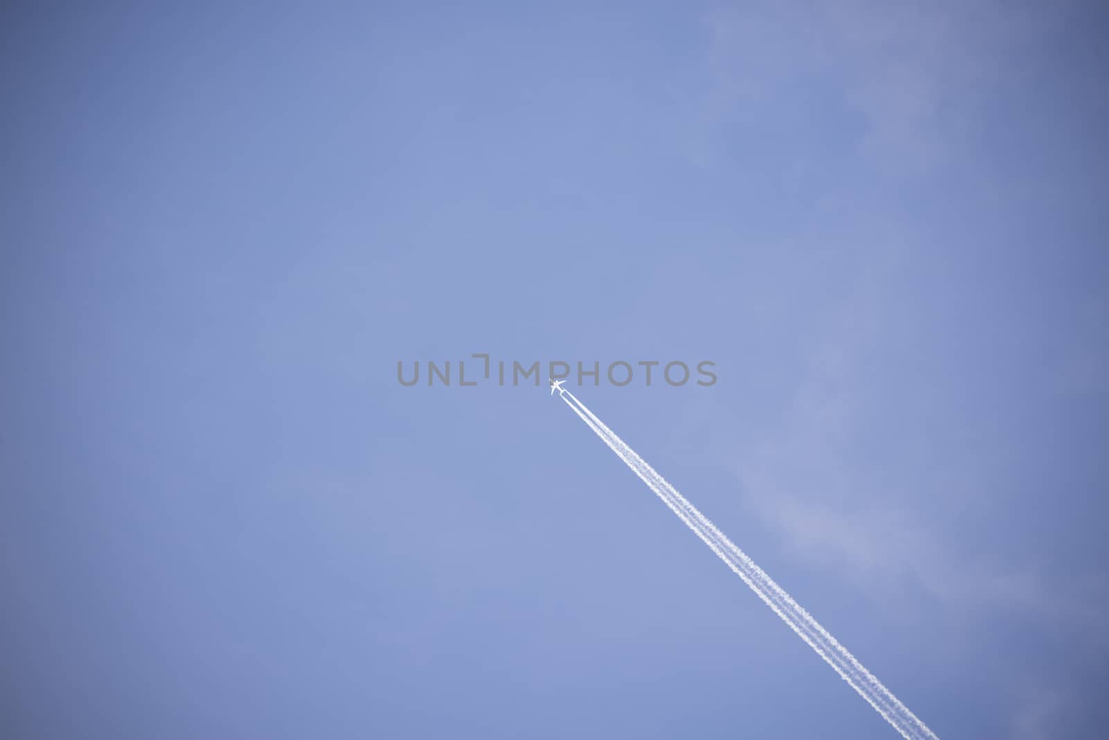 jet and its vapour trails in a cloudy blue sky