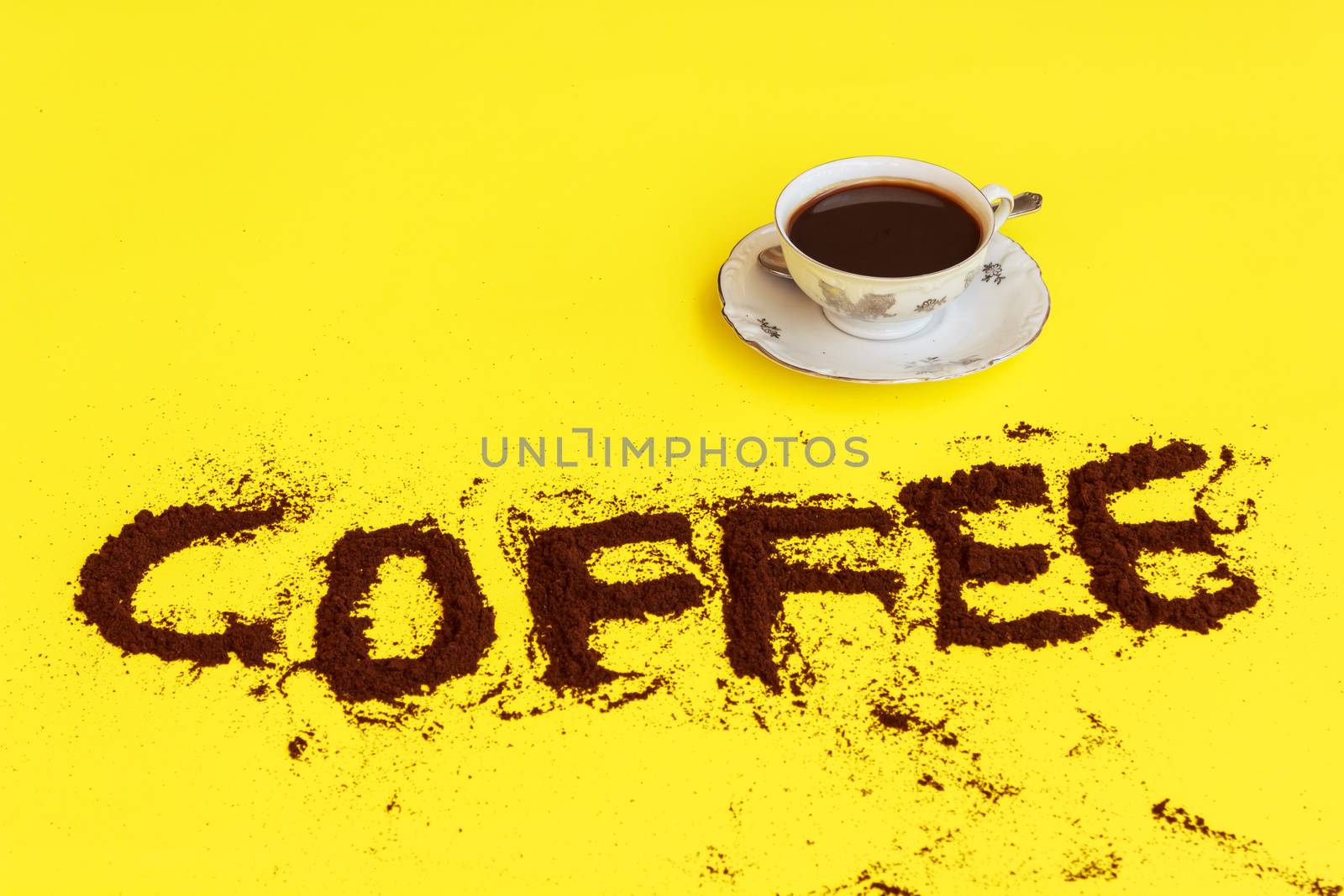 a cup full of coffee ready to drink with the word coffee drawn with coffee grounds