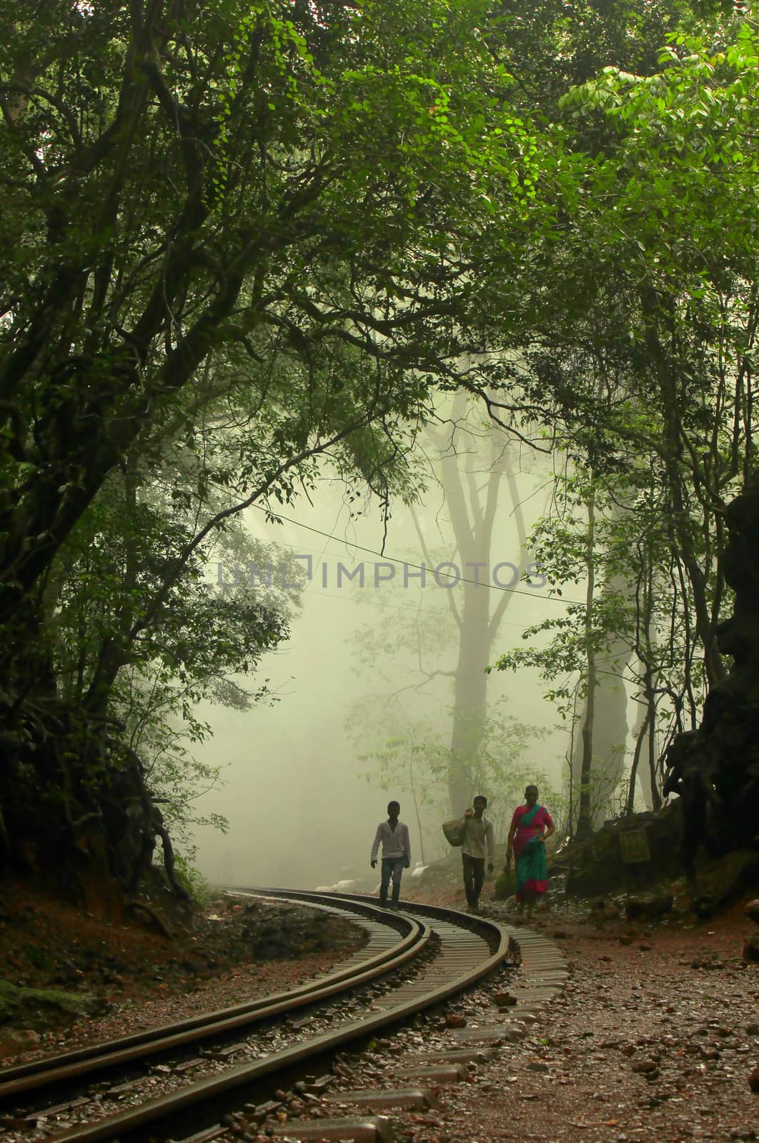 People walk up a railway track on a hillstation in India during early morning hours