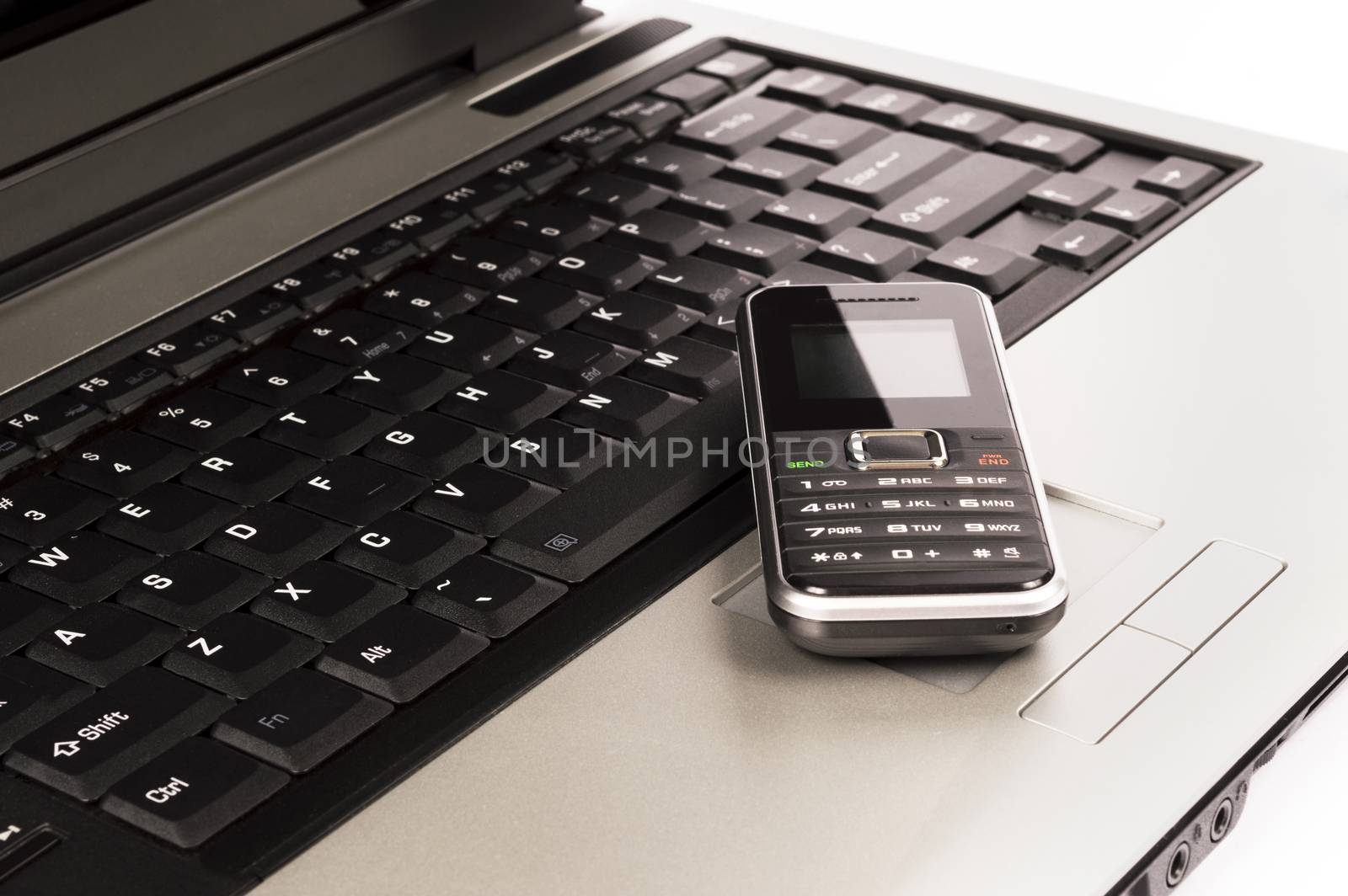 Mobile Phone On Laptop Keyboard by stockbuster1