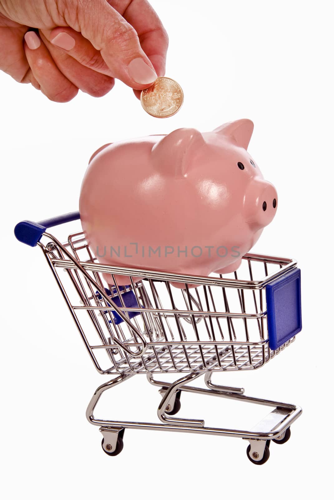 Saving money when shopping concept.  Hand putting coin into piggy bank sitting in shopping cart.