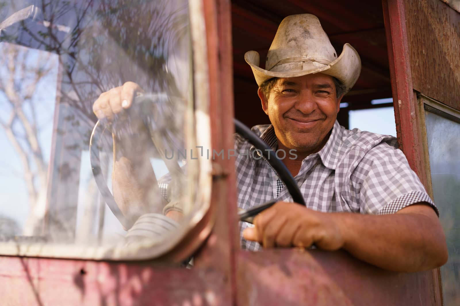 Portrait Happy Man Farmer Driving Tractor Looking At Camera by diego_cervo