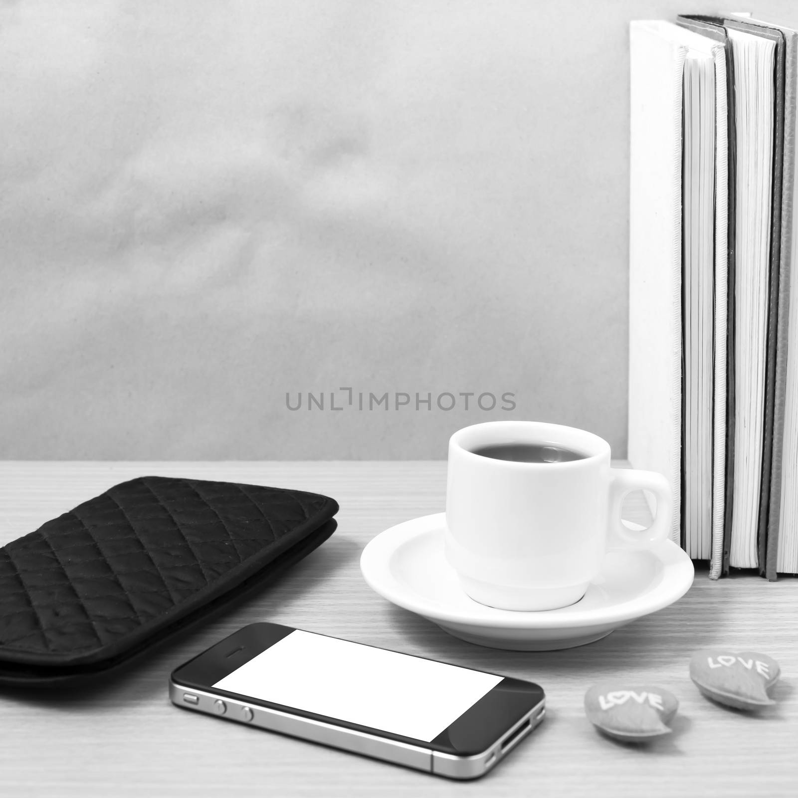 office desk : coffee with phone,heart,stack of book,wallet on wood background black and white color