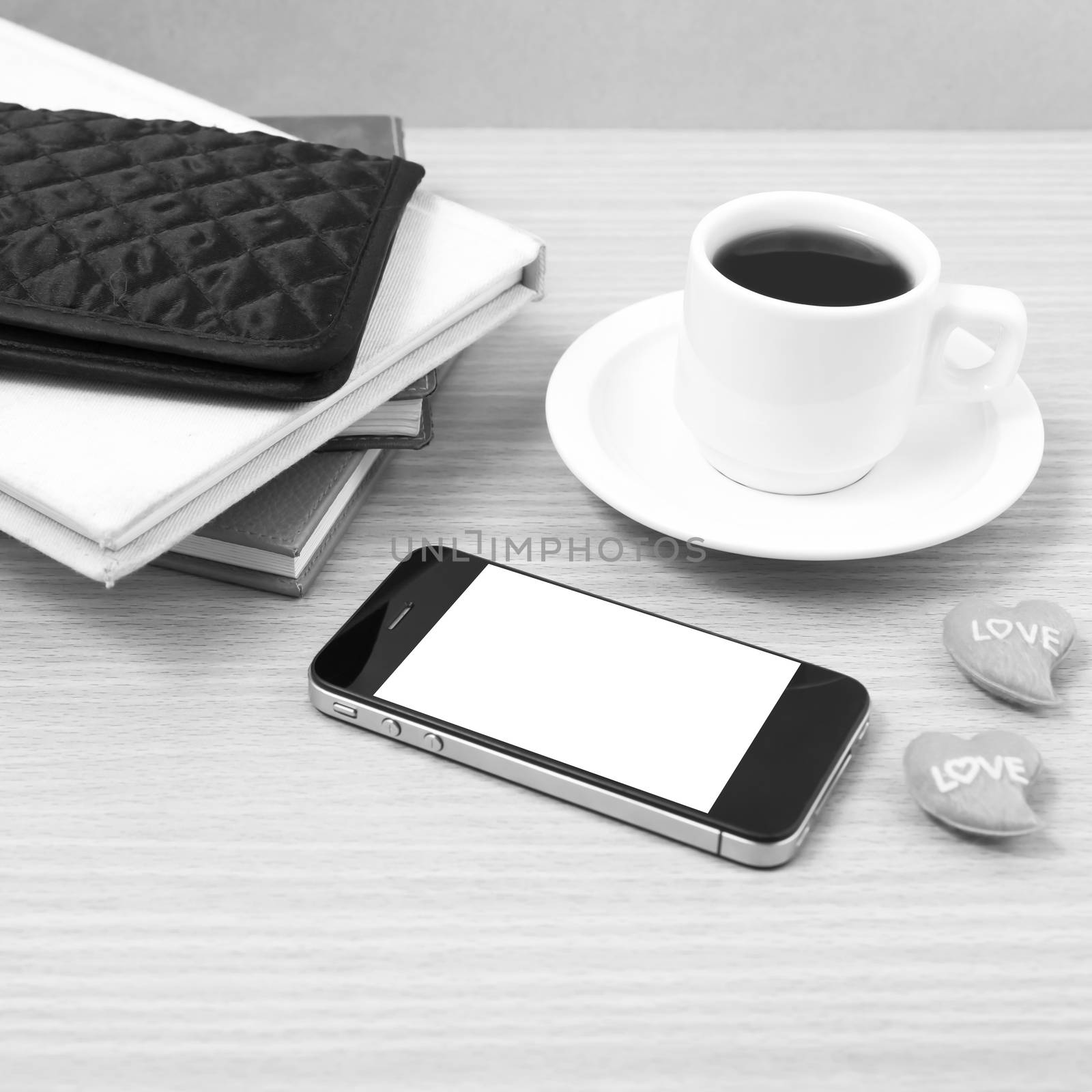 office desk : coffee with phone,heart,stack of book,wallet on wood background black and white color