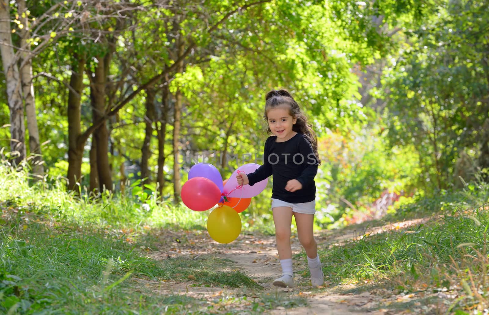 Little girl playing in autumn park with balloons