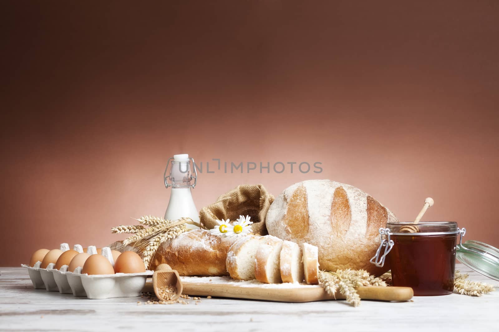 Freshly baked bread,honey and eggs on wooden vintage table