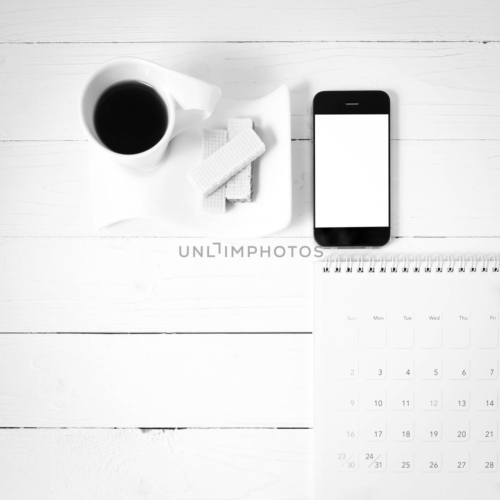 coffee cup with wafer,phone,calendar on white wood background black and white color