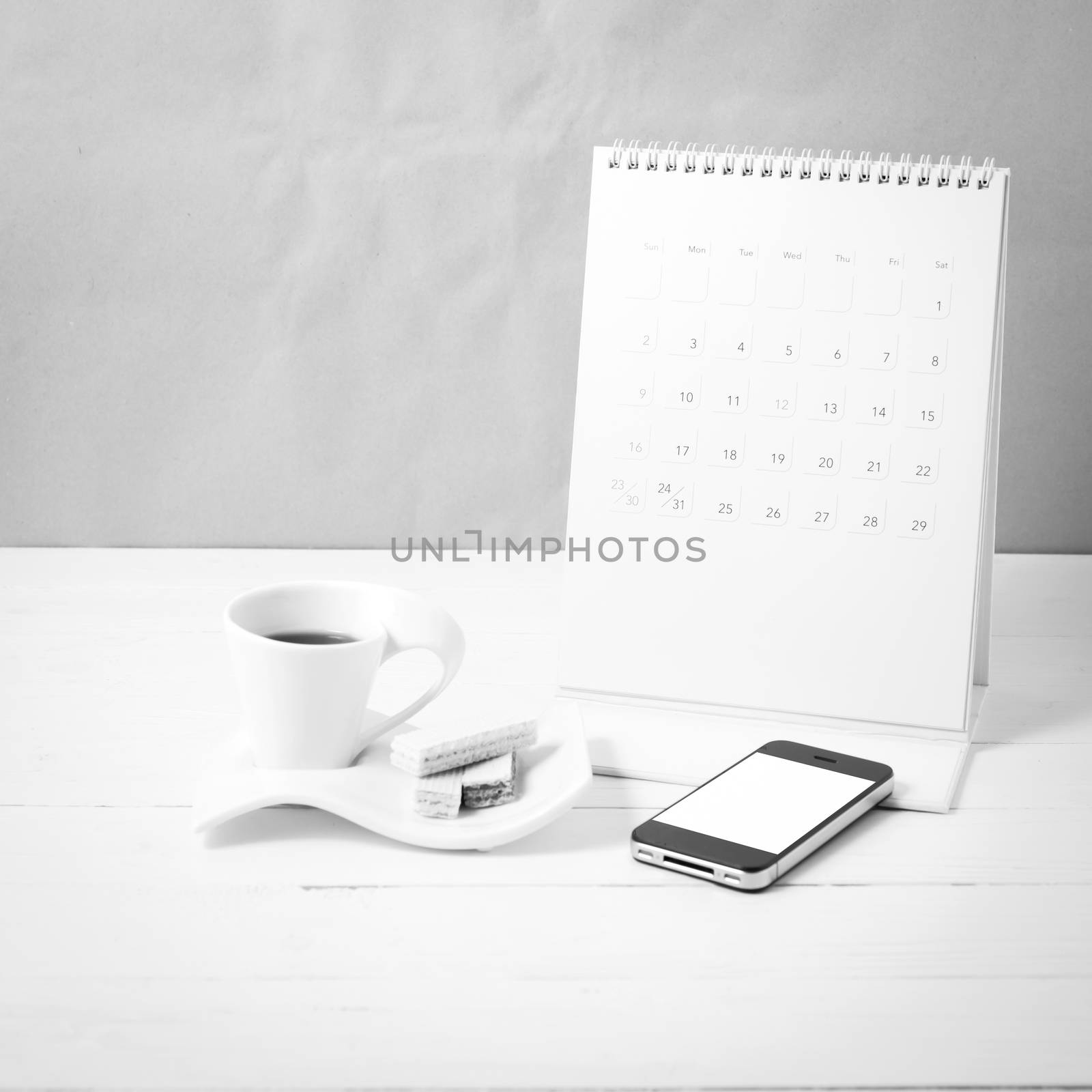 coffee cup with wafer,phone,calendar on white wood background black and white color