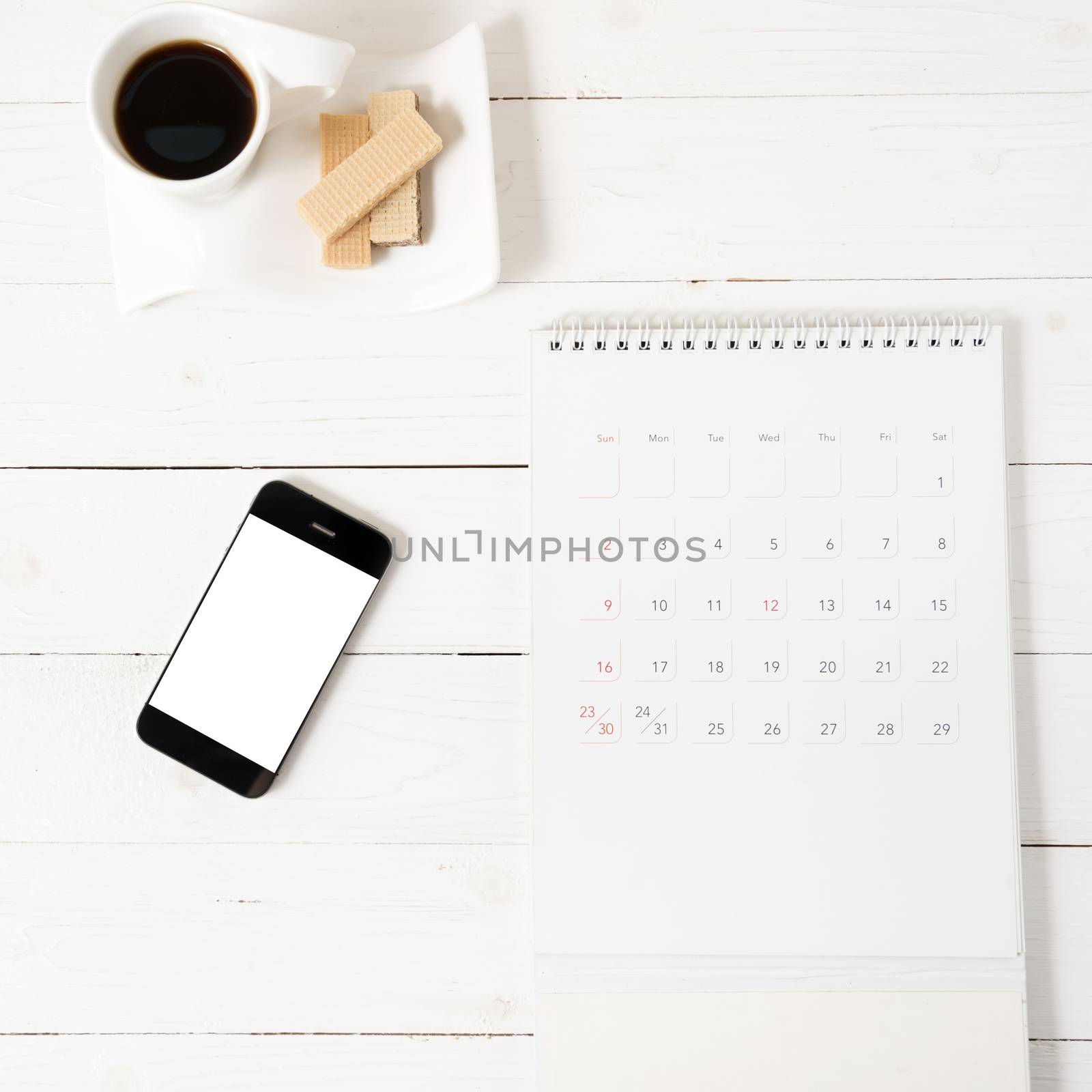 coffee cup with wafer,phone,calendar on white wood background