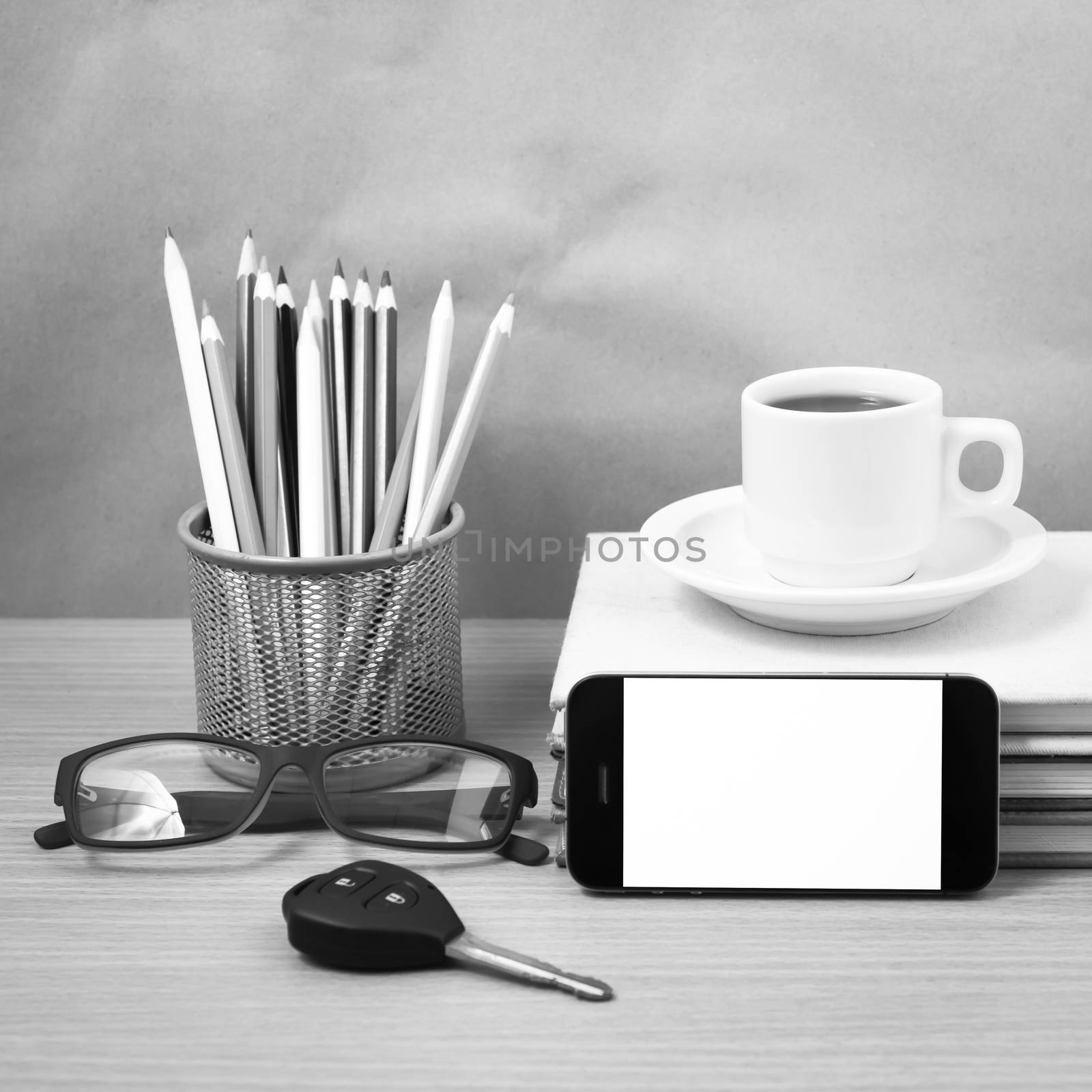 office desk : coffee and phone with car key,eyeglasses,stack of book,pencil box black and white color