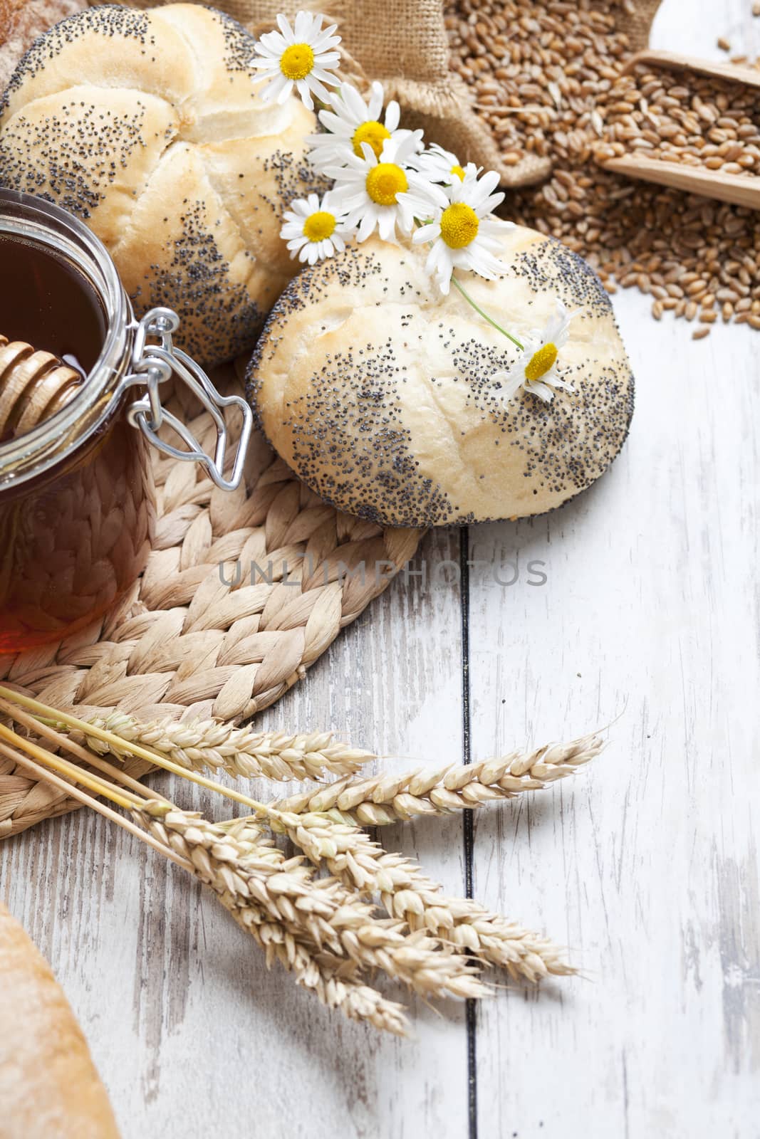 Freshly baked bread rolls, wheat ears and honey