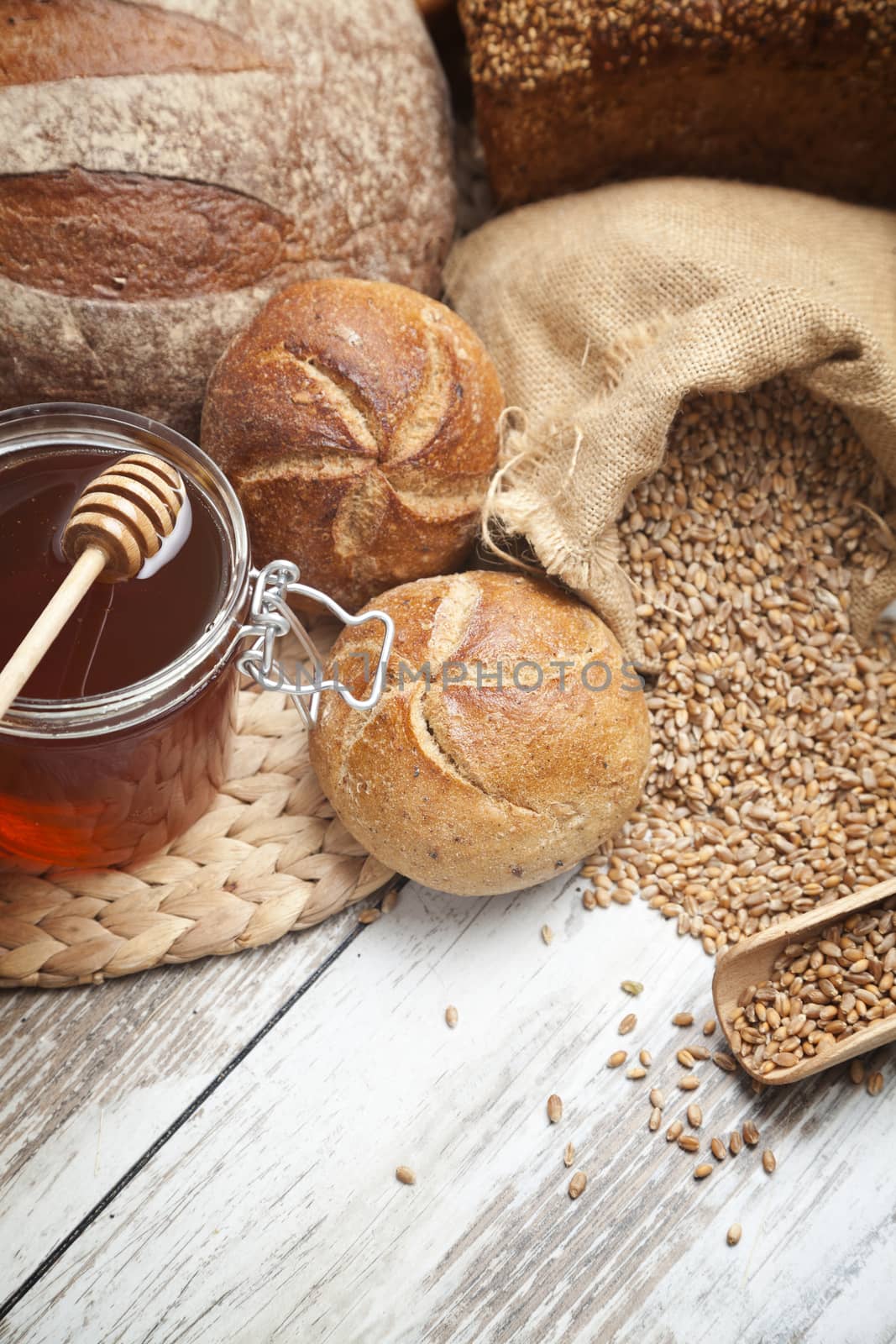 Freshly baked bread rolls, wheat ears and honey