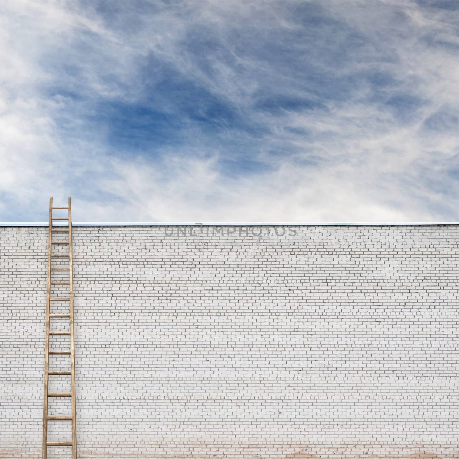 huge white brick wall with a wooden ladder and cloudy sky background