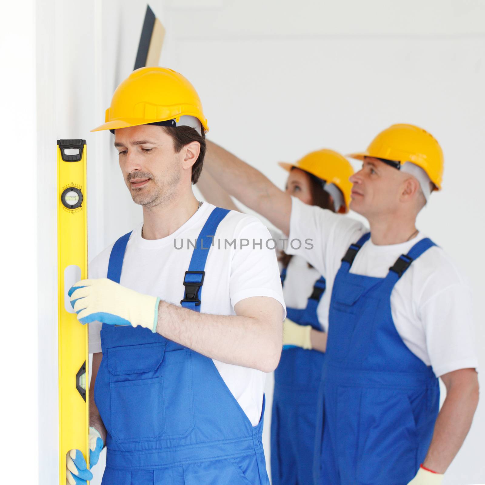 Building teamwork concept - group of smiling builders in hardhats with tools indoors