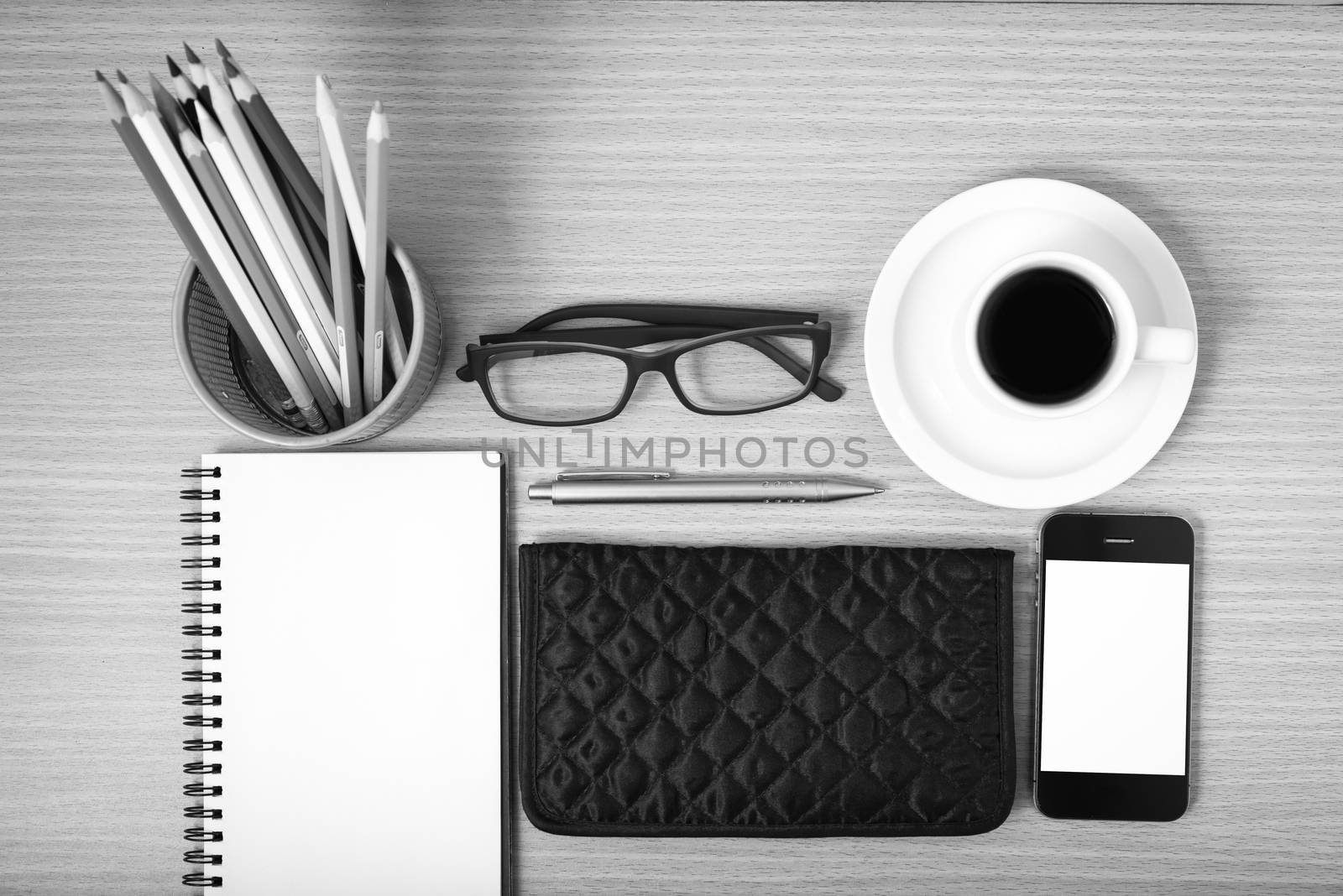 office desk : coffee with phone,notepad,eyeglasses,wallet,color pencil box on wood background black and white color