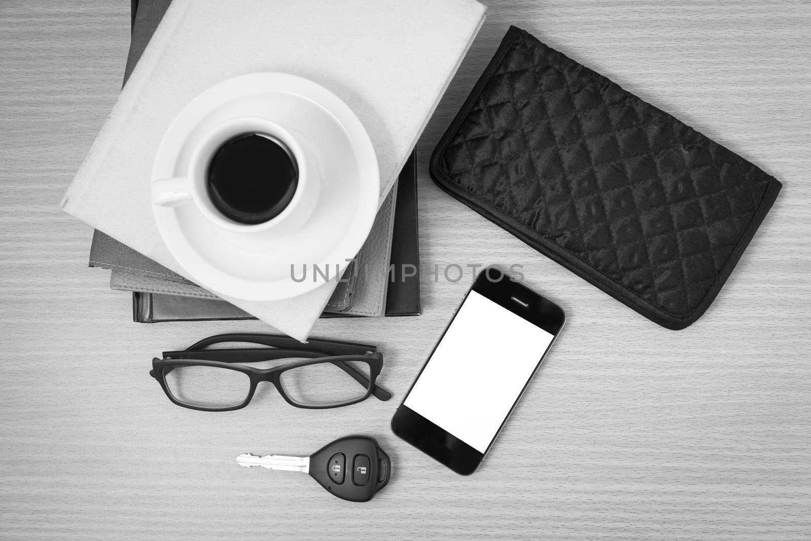 coffee and phone with stack of book,car key,eyeglasses and wallet on wood background black and white color