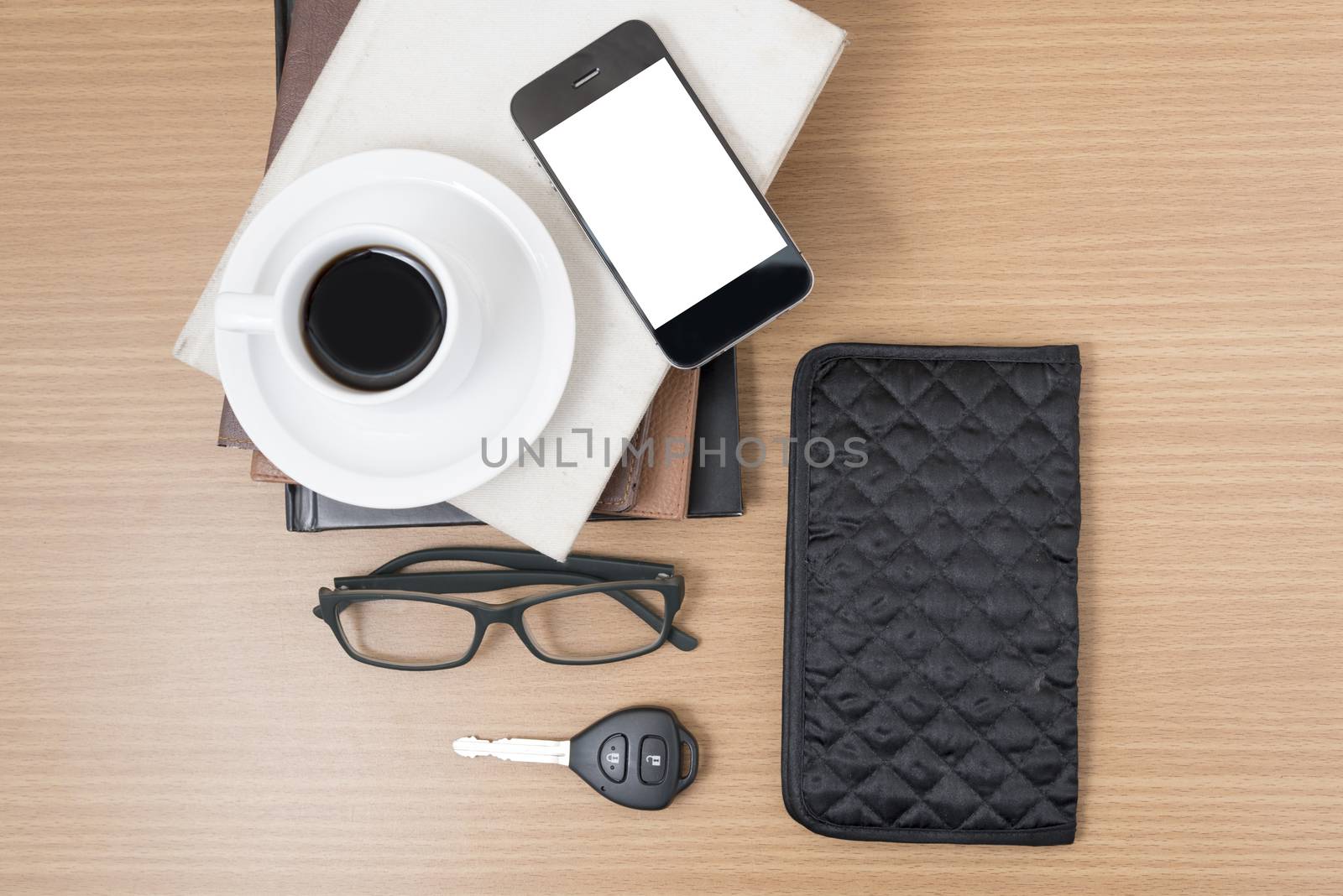 coffee and phone with stack of book,car key,eyeglasses and wallet on wood background