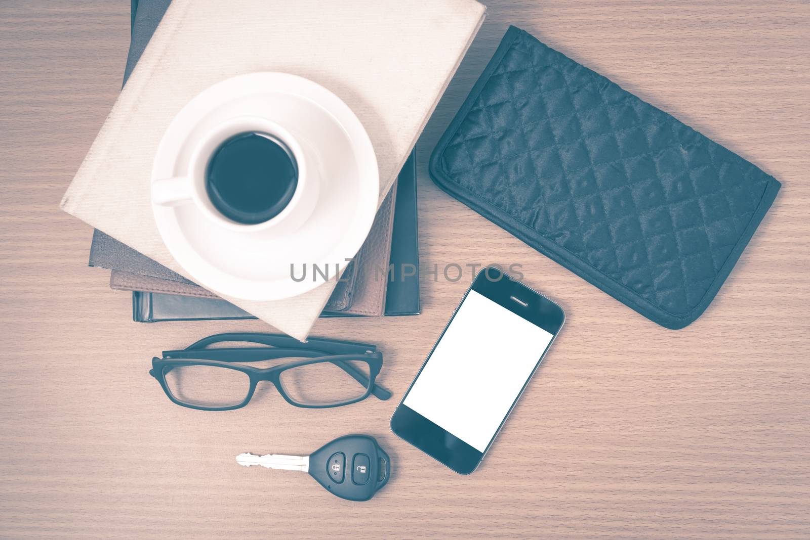 coffee and phone with stack of book,car key,eyeglasses and wallet on wood background vintage style