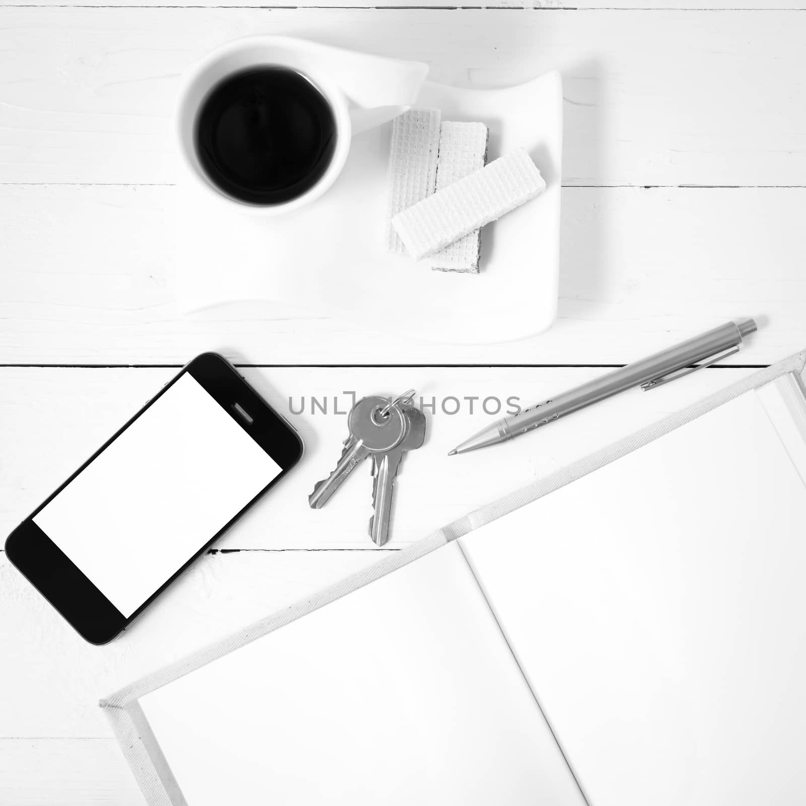 coffee cup with wafer,phone,key,notebook on white wood background black and white color