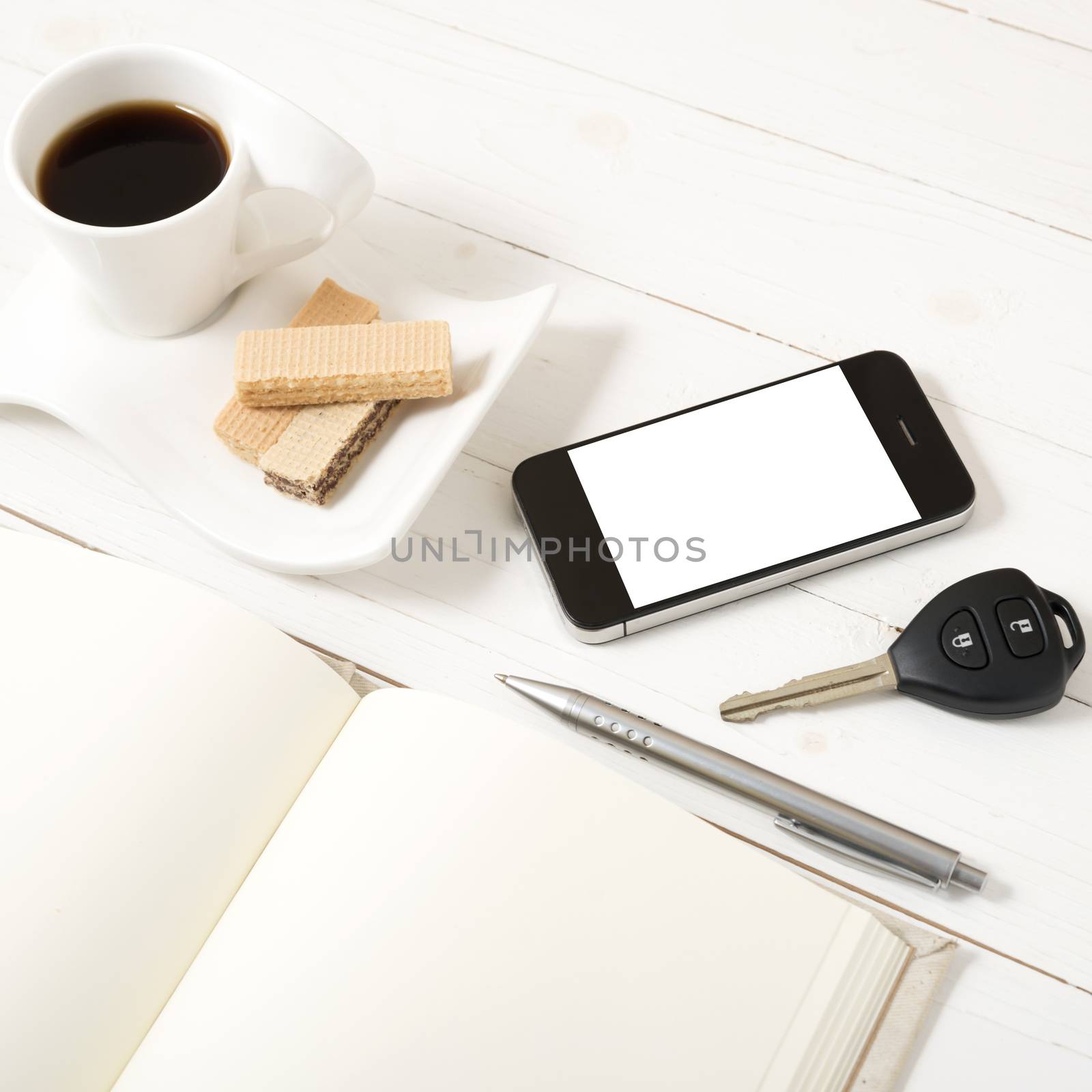 coffee cup with wafer,phone,car key,notebook on white wood background