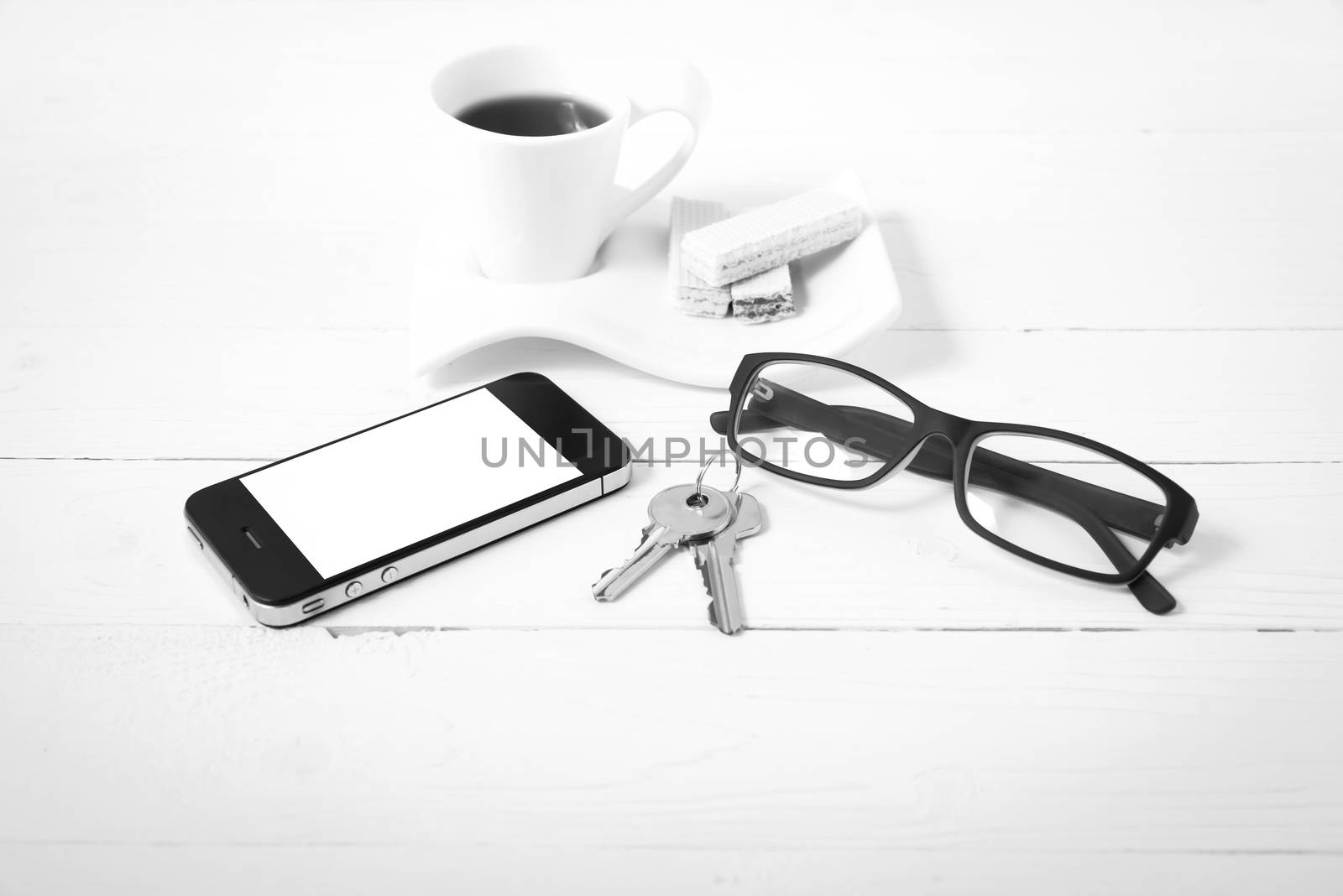 coffee cup with wafer,phone,key,eyeglasses on white wood background black and white color