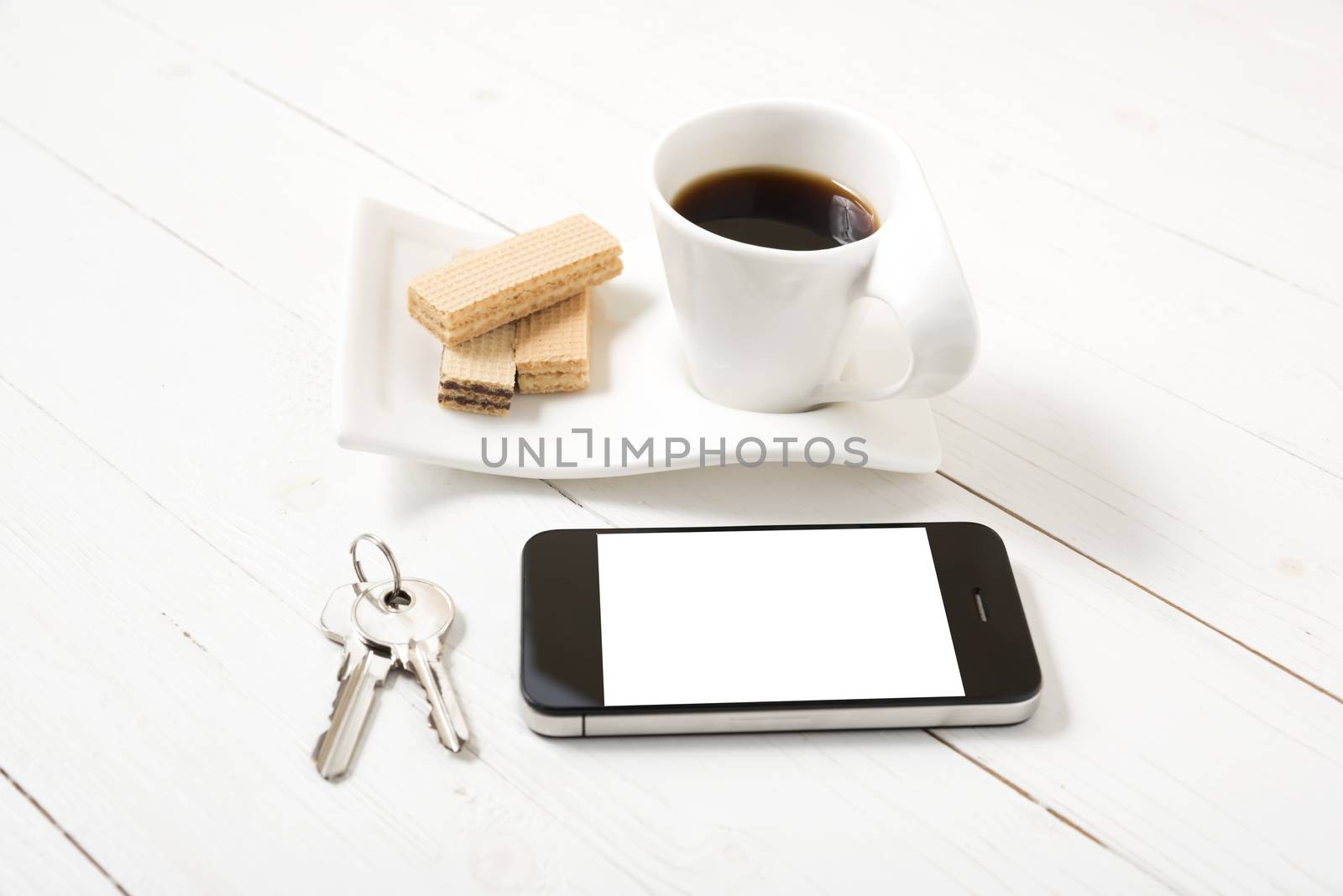 coffee cup with wafer,phone,key on white wood background