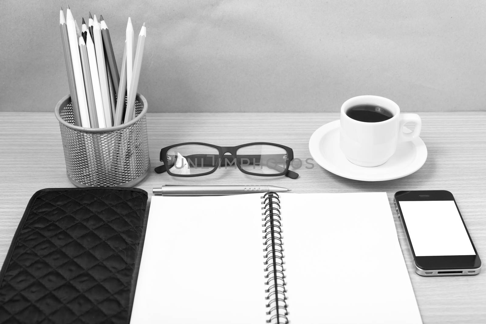 office desk : coffee with phone,notepad,eyeglasses,wallet,color pencil box on wood background black and white color