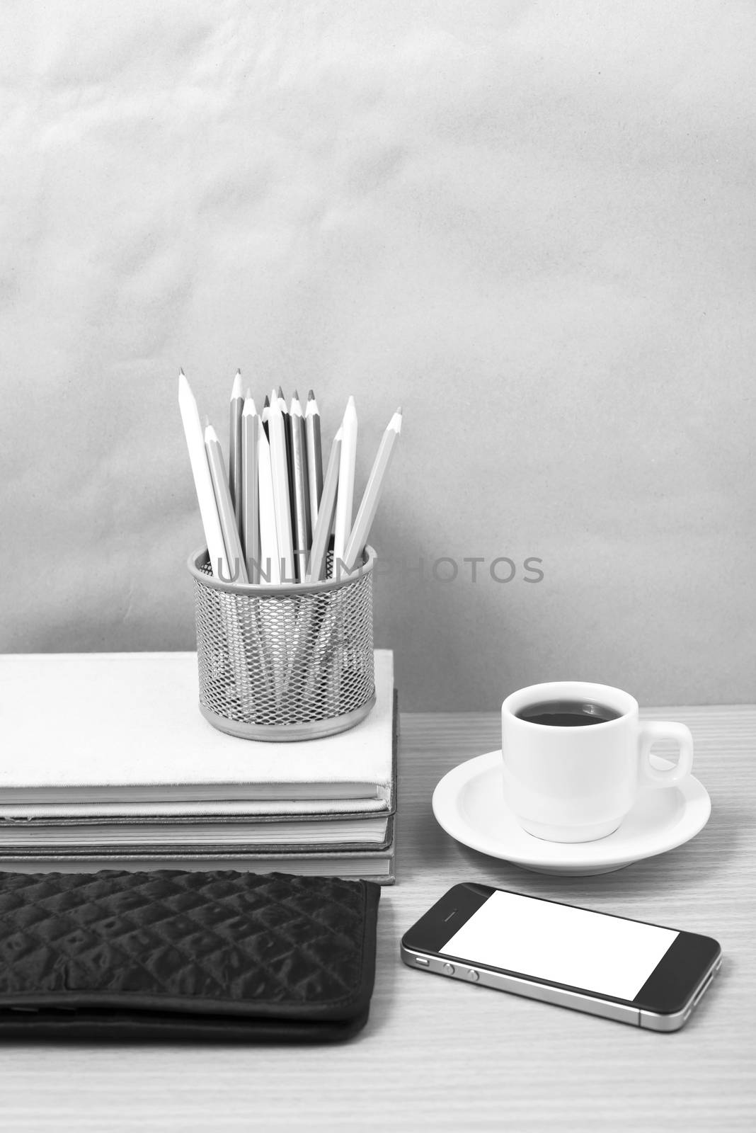 office desk : coffee with phone,stack of book,wallet,color box on wood background black and white color