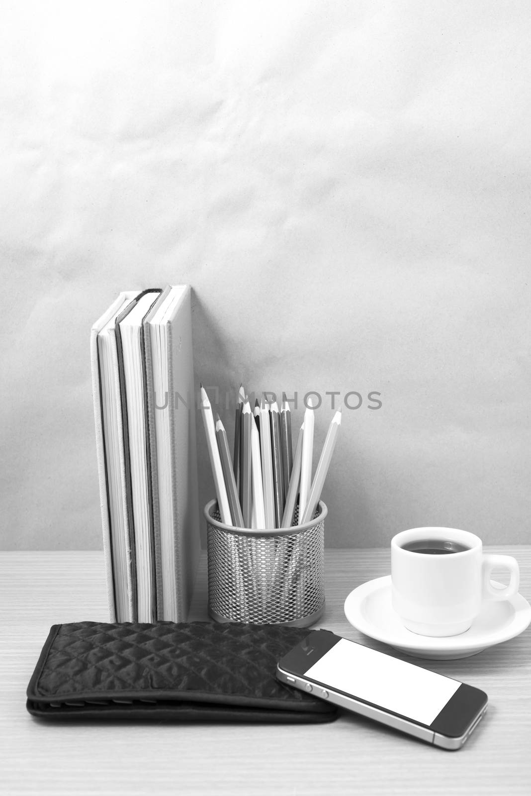 office desk : coffee with phone,stack of book,wallet,color box on wood background black and white color