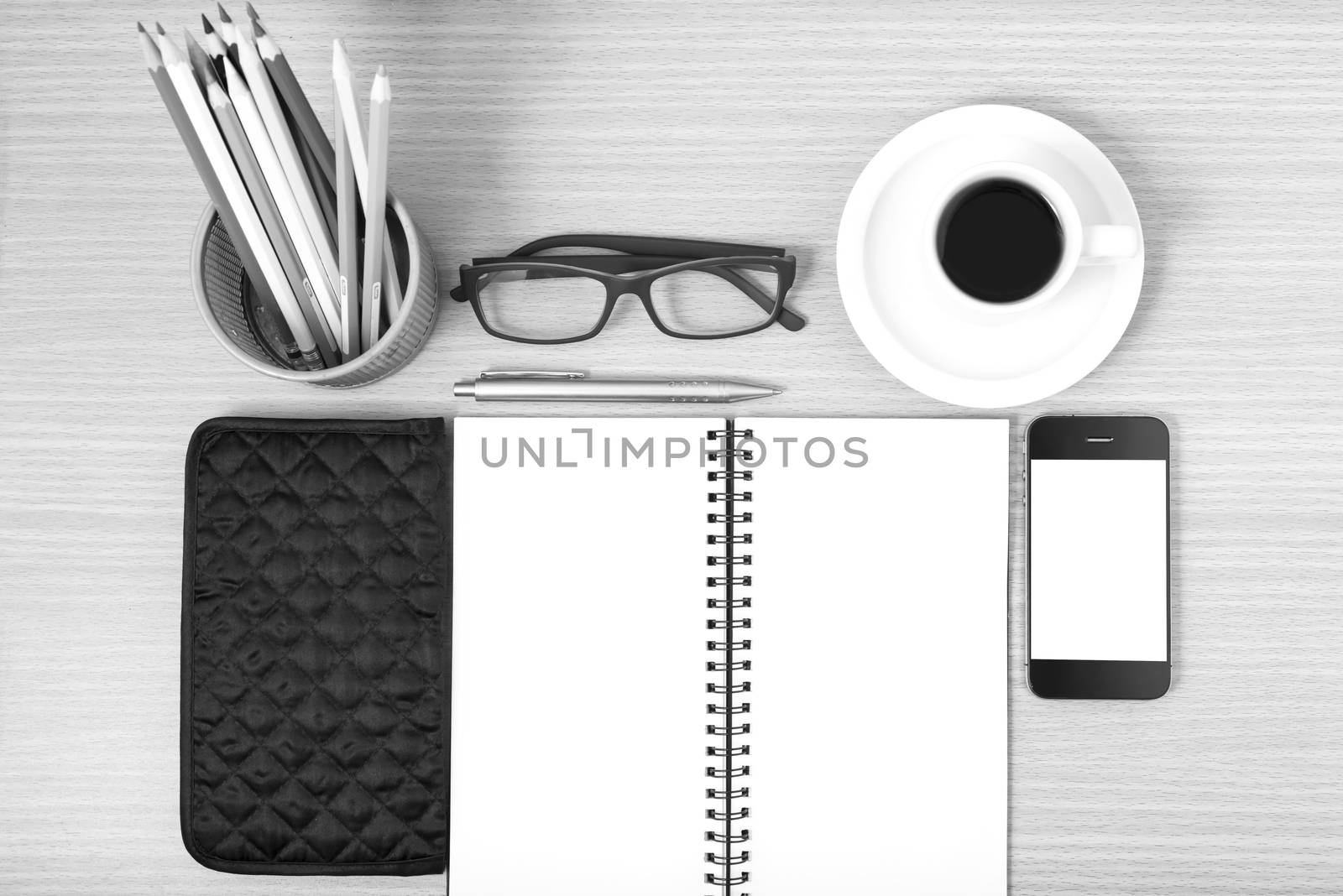 office desk : coffee with phone,notepad,eyeglasses,wallet,color pencil box on wood background black and white color