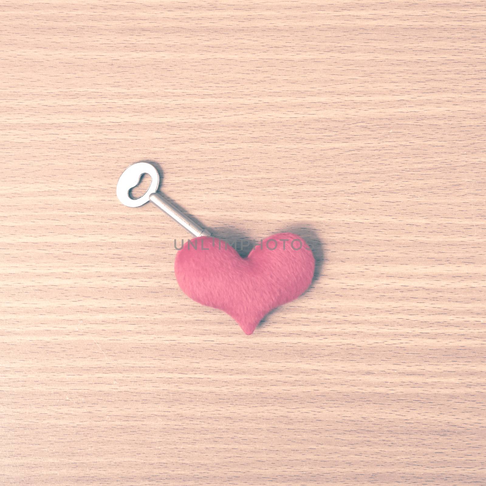 red heart with key on wood table background vintage style