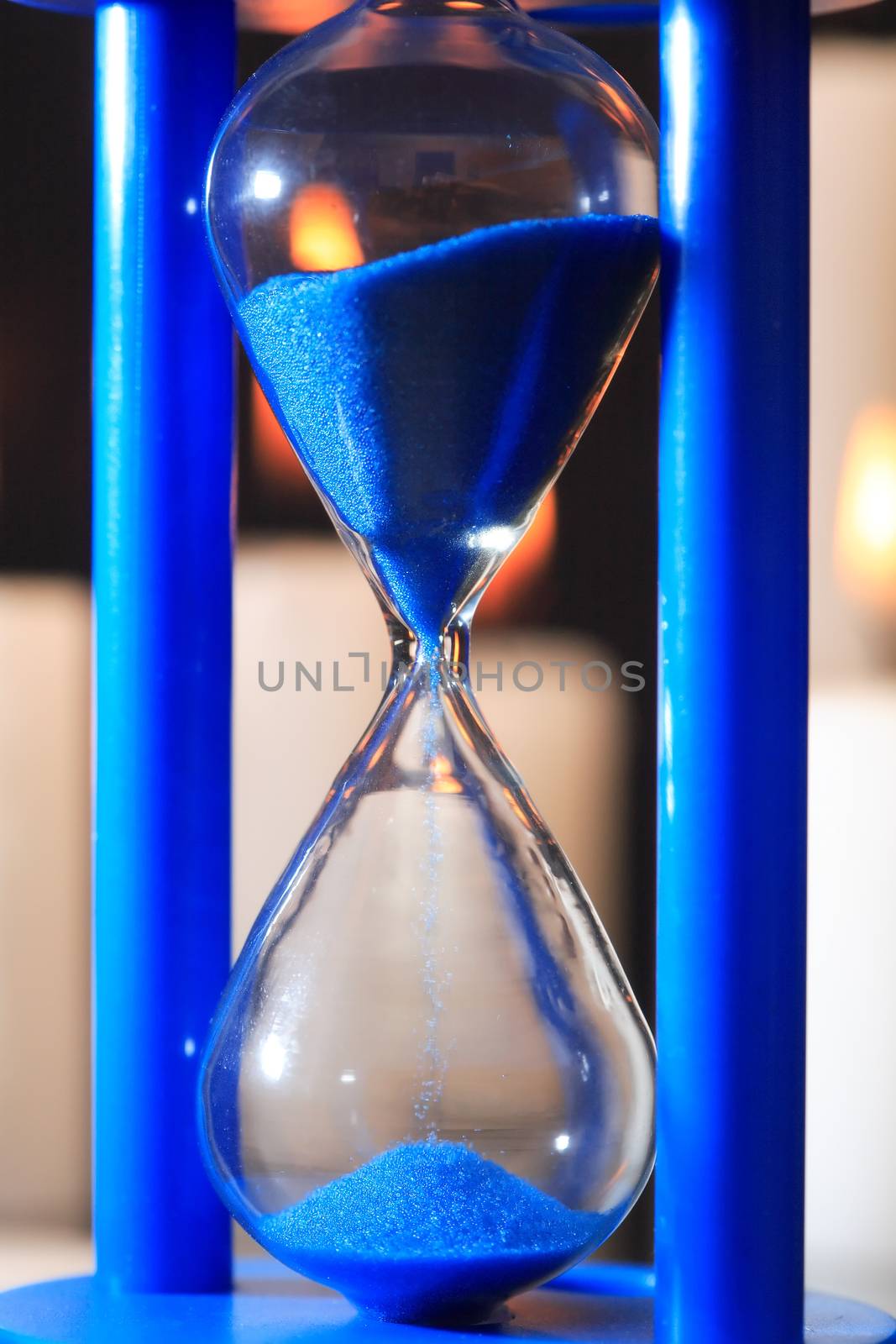Extreme closeup of blue vintage hourglass with flowing sand