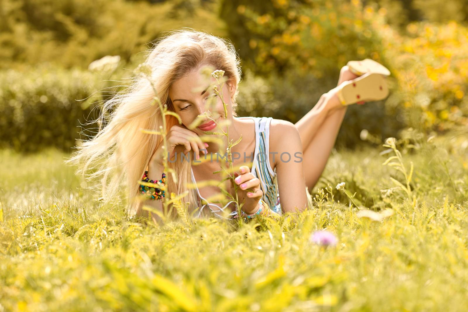 Beauty playful woman relax in summer garden dreaming on grass, people, outdoors, bokeh. Attractive happy blonde girl enjoying nature, harmony on meadow, lifestyle.Sunny day, forest, flowers, copyspace