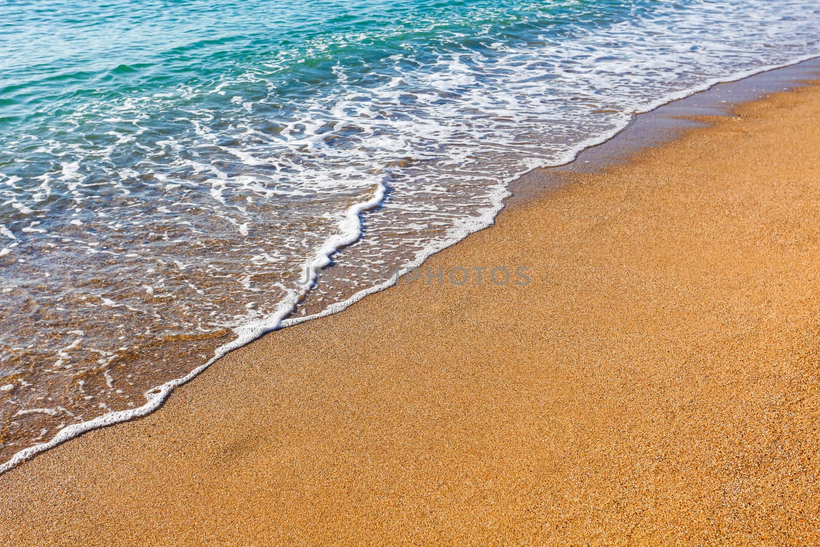 Sun light reflected on soft wave of the sea on the sandy beach