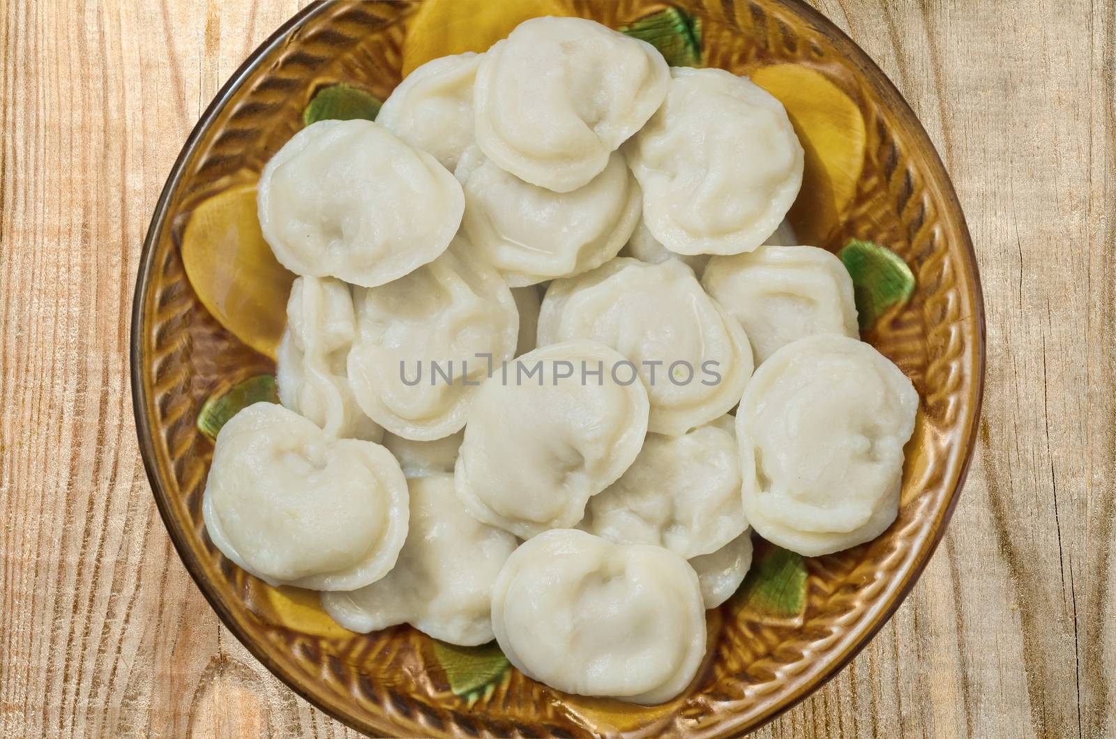 Ceramic bowl of boiled dumplings is on the boards by Gaina