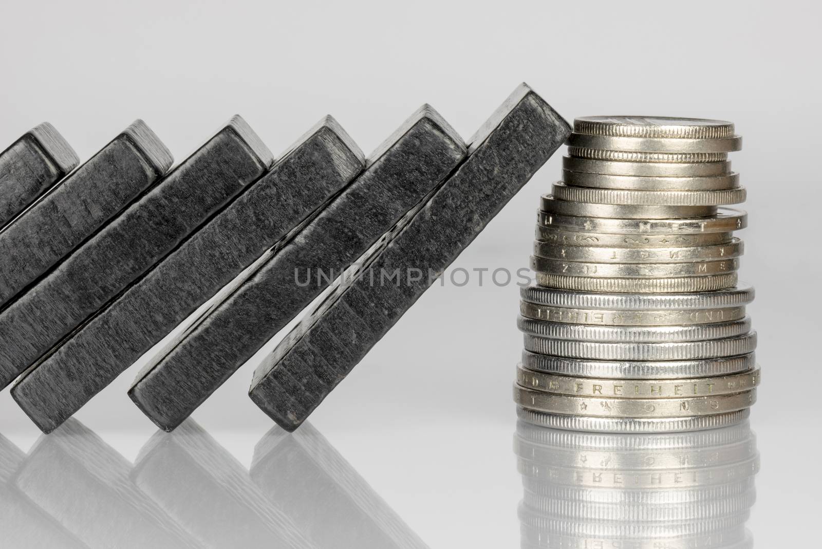 Conceptual composition of falling black domino stones as a continuous process and a pile of coins which disrupt this main process
