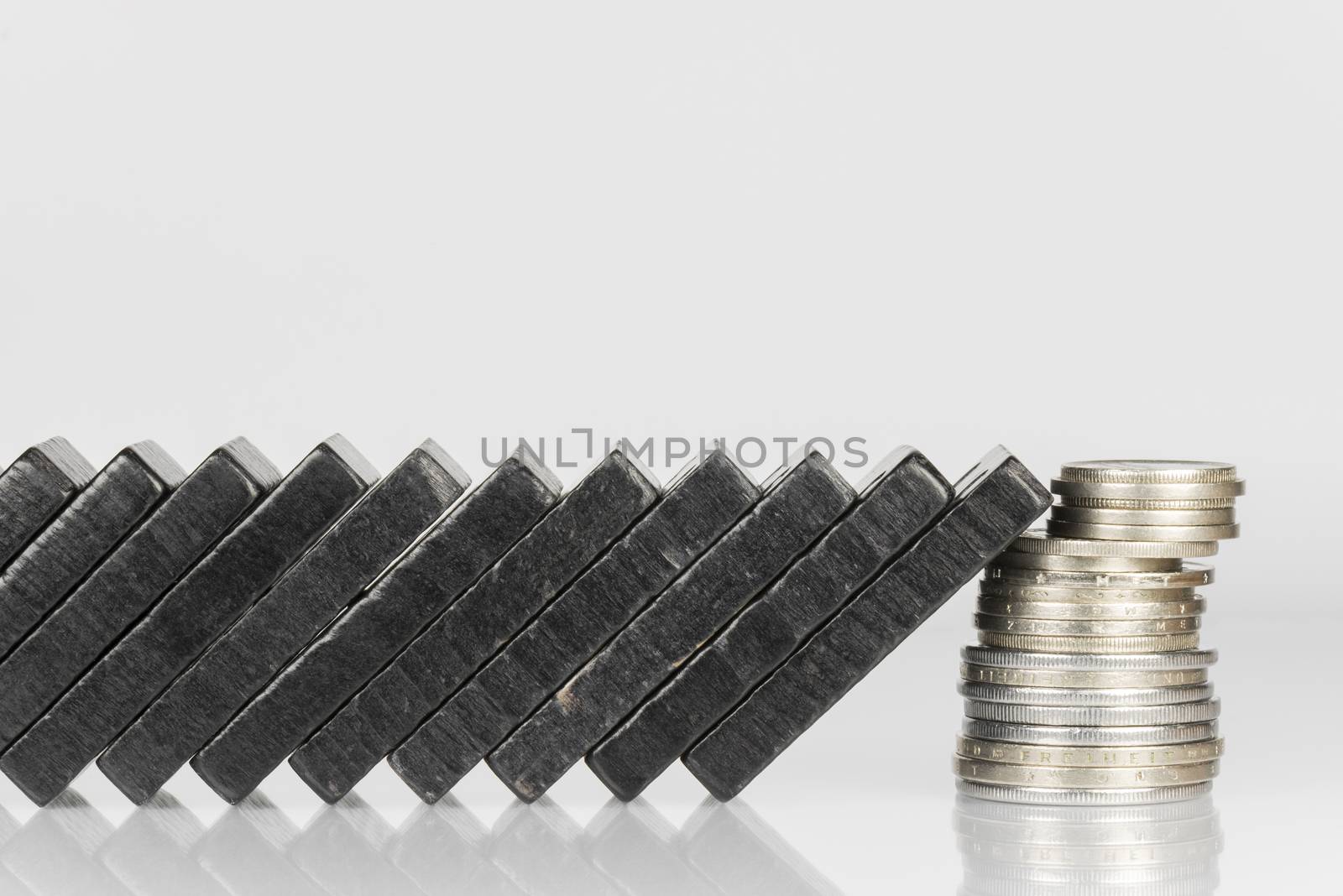 Conceptual composition of falling black domino stones as a continuous process and a pile of coins which disrupt this main process
