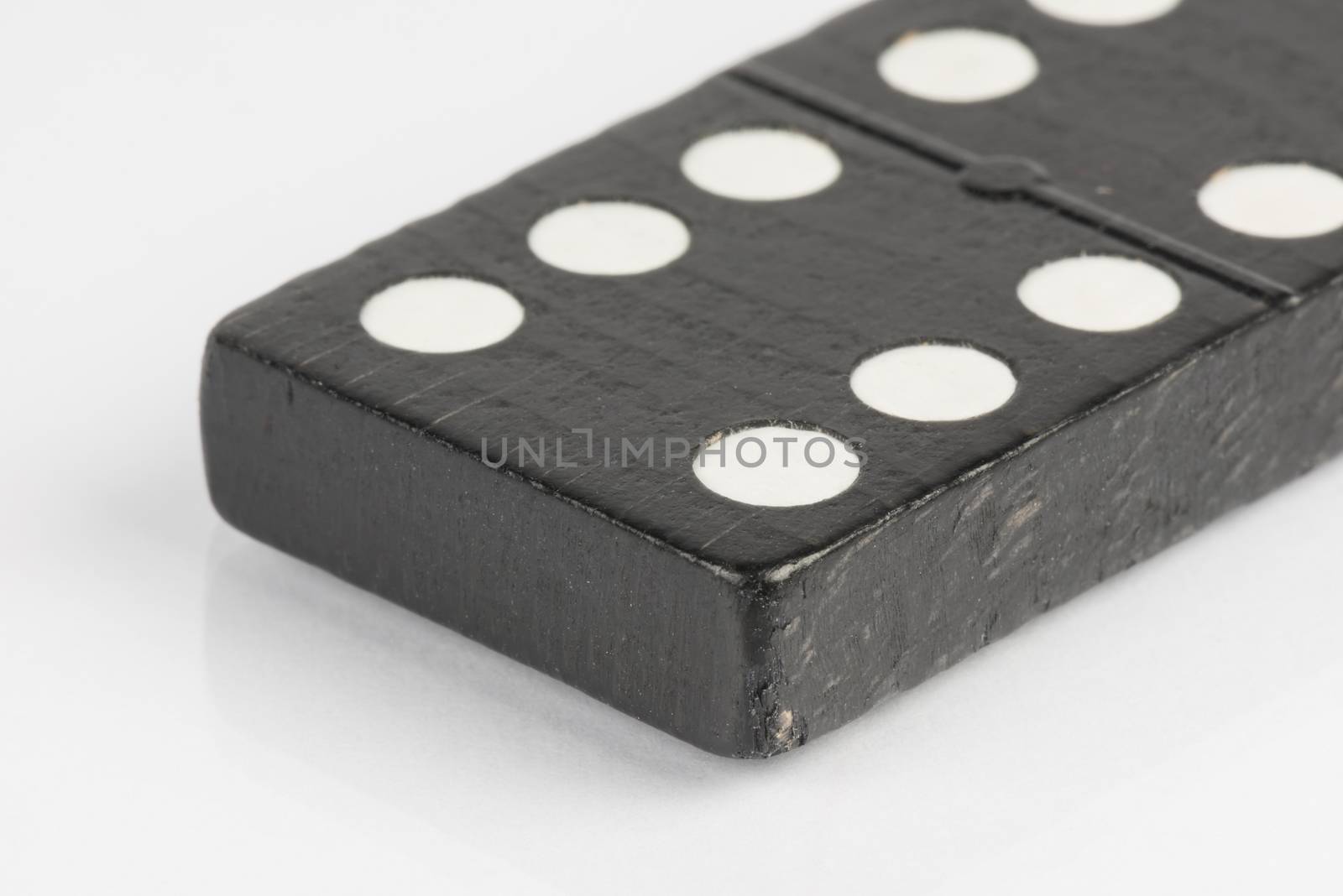 Lying black domino brick with white dots
