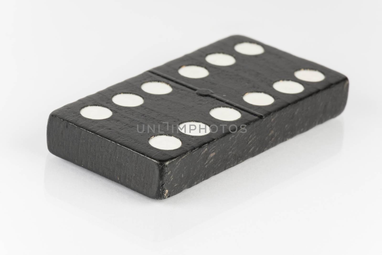 Lying black domino brick with white dots
