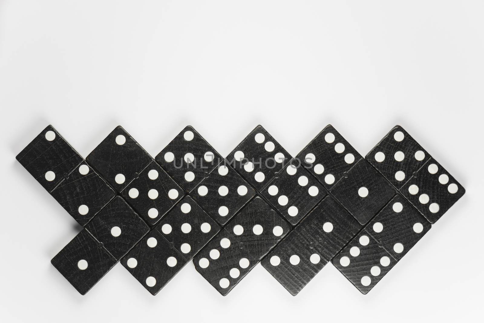 Composition of lying black domino bricks with white dots
