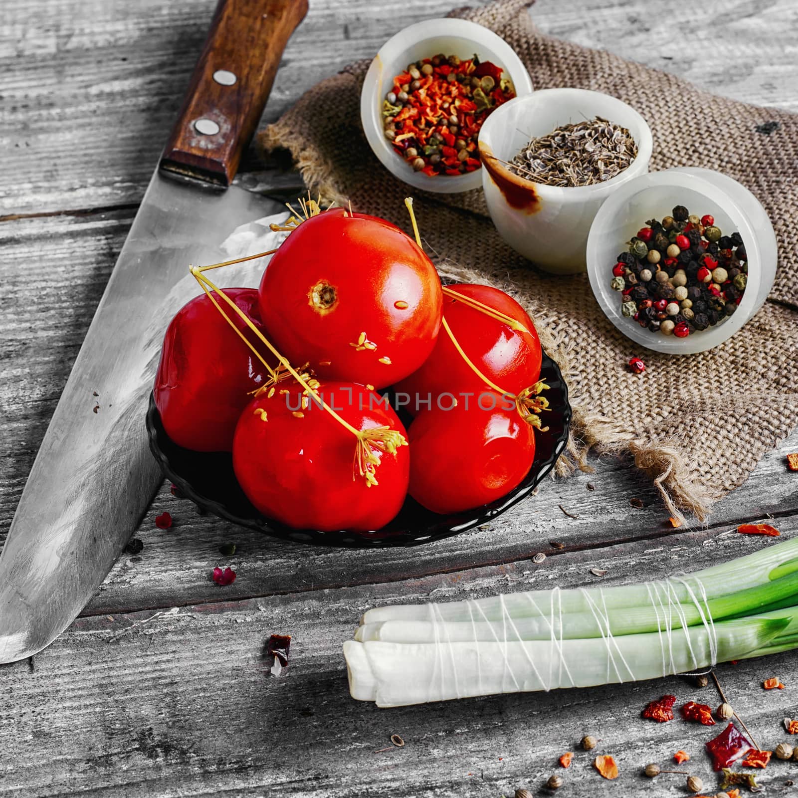 Saucer of pickled tomatoes on wooden background in rustic style