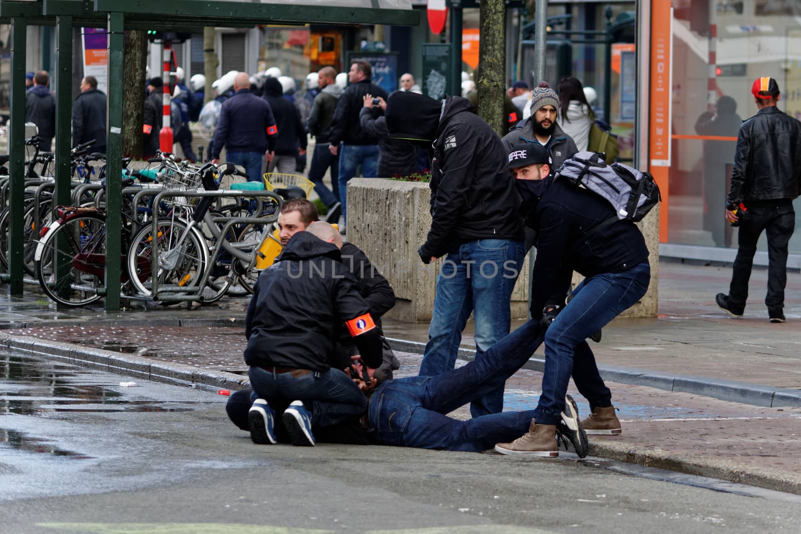 BELGIUM, Brussels: Policemen arrest a man after clash between police and far-right mob at Bourse square in Brussels on March 27, 2016 an area which has become an unofficial shrine to victims of the March 22, terror attacks claimed by the Islamic State (IS) group in which 31 people were killed and over 300 injured. Riot police fired water cannon on March 27, 2016 at far-right football hooligans who invaded a square in the Belgian capital that has become a memorial to the victims of the Brussels attacks. Police took action after about 200 black-clad hooligans shouting nationalist and anti-immigrant slogans moved in on the Place de la Bourse where people were gathering in a show of solidarity with the victims.