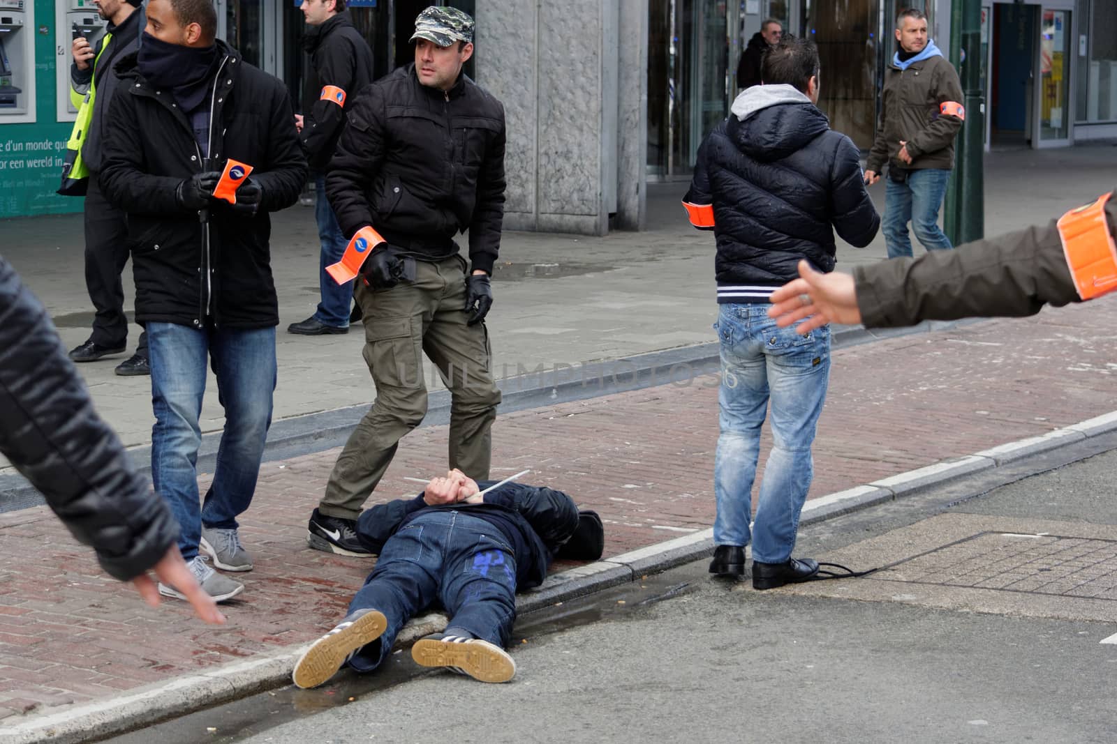 BELGIUM, Brussels: Policemen arrest a man after clash between police and far-right mob at Bourse square in Brussels on March 27, 2016 an area which has become an unofficial shrine to victims of the March 22, terror attacks claimed by the Islamic State (IS) group in which 31 people were killed and over 300 injured. Riot police fired water cannon on March 27, 2016 at far-right football hooligans who invaded a square in the Belgian capital that has become a memorial to the victims of the Brussels attacks. Police took action after about 200 black-clad hooligans shouting nationalist and anti-immigrant slogans moved in on the Place de la Bourse where people were gathering in a show of solidarity with the victims.