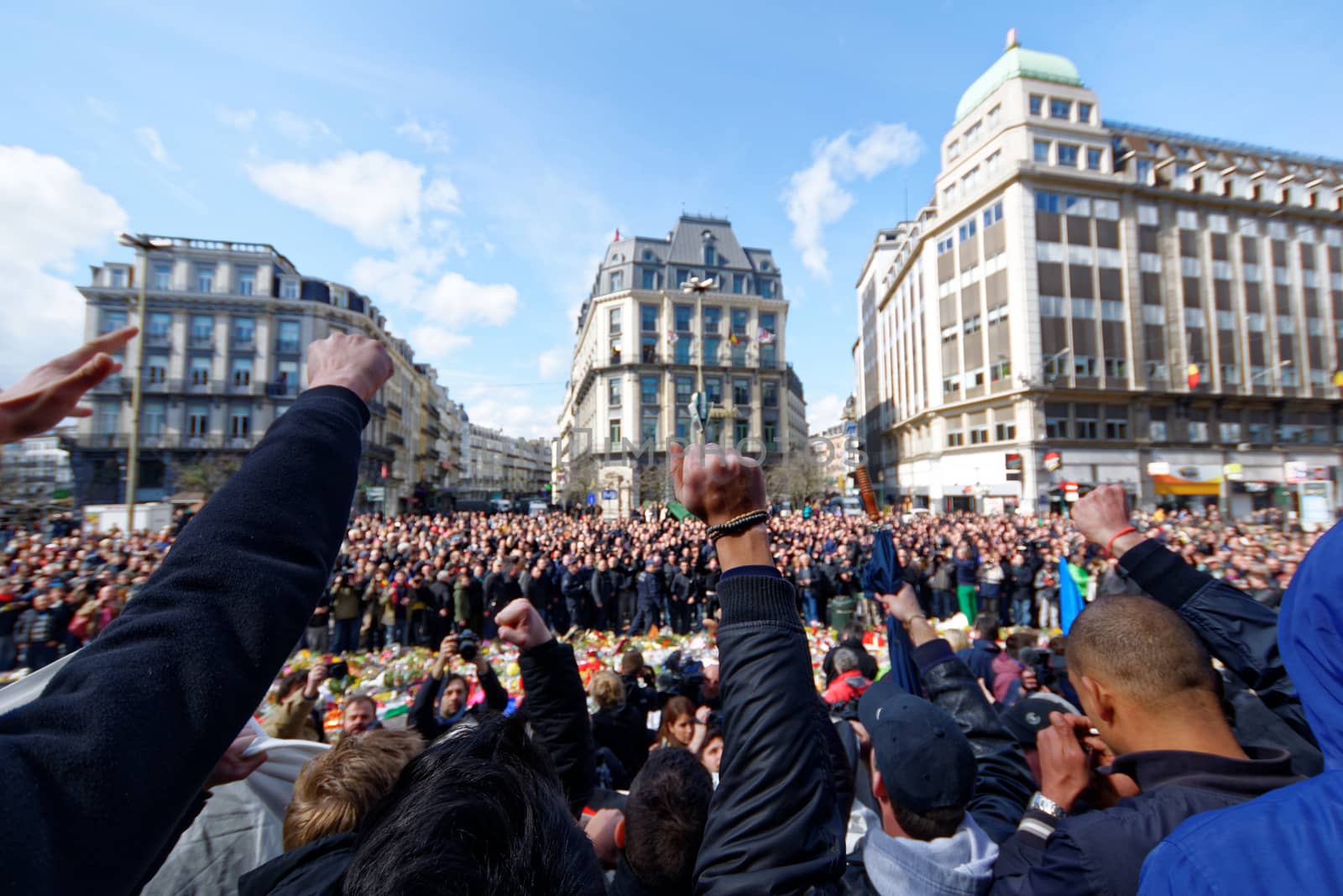 BELGIUM, Brussels : Far-right football hooligans chant slogans as they stand in the square outside the stock exchange in Brussels on March 27, 2016 an area which has become an unofficial shrine to victims of the March 22, terror attacks claimed by the Islamic State (IS) group in which 31 people were killed and over 300 injured.Police fired water a cannon at far-right football hooligans who invaded a square in the Belgian capital that has become a memorial to the victims of the Brussels attacks, an AFP journalist said. Police took action after about 200 black-clad hooligans shouting nationalist and anti-immigrant slogans moved in on the Place de la Bourse where people were gathering in a show of solidarity with the victims.