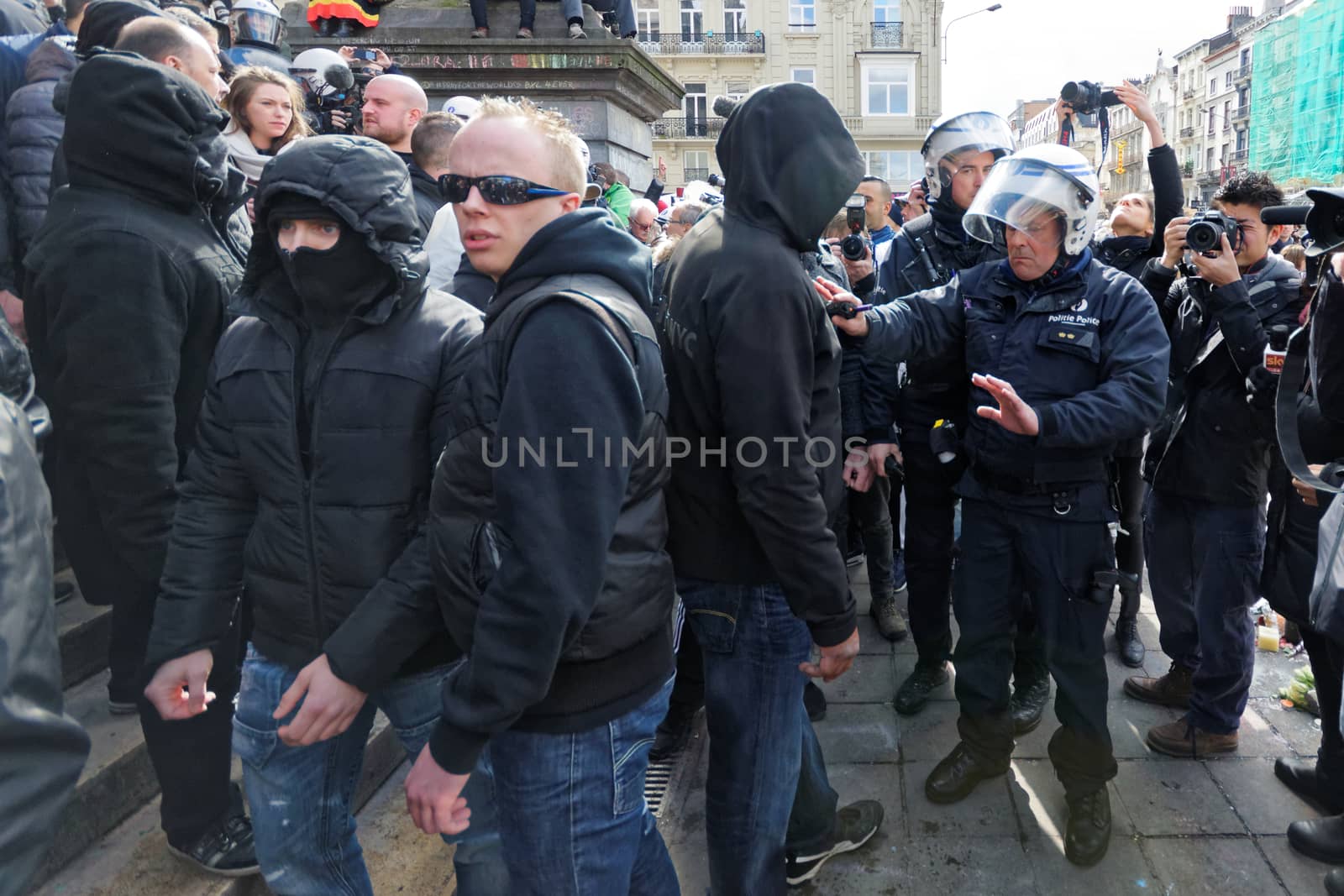 BELGIUM, Brussels : Far-right football hooligans face police outside the stock exchange in Brussels on March 27, 2016 an area which has become an unofficial shrine to victims of the March 22, terror attacks claimed by the Islamic State (IS) group in which 31 people were killed and over 300 injured.Police fired water a cannon at far-right football hooligans who invaded a square in the Belgian capital that has become a memorial to the victims of the Brussels attacks, an AFP journalist said. Police took action after about 200 black-clad hooligans shouting nationalist and anti-immigrant slogans moved in on the Place de la Bourse where people were gathering in a show of solidarity with the victims.