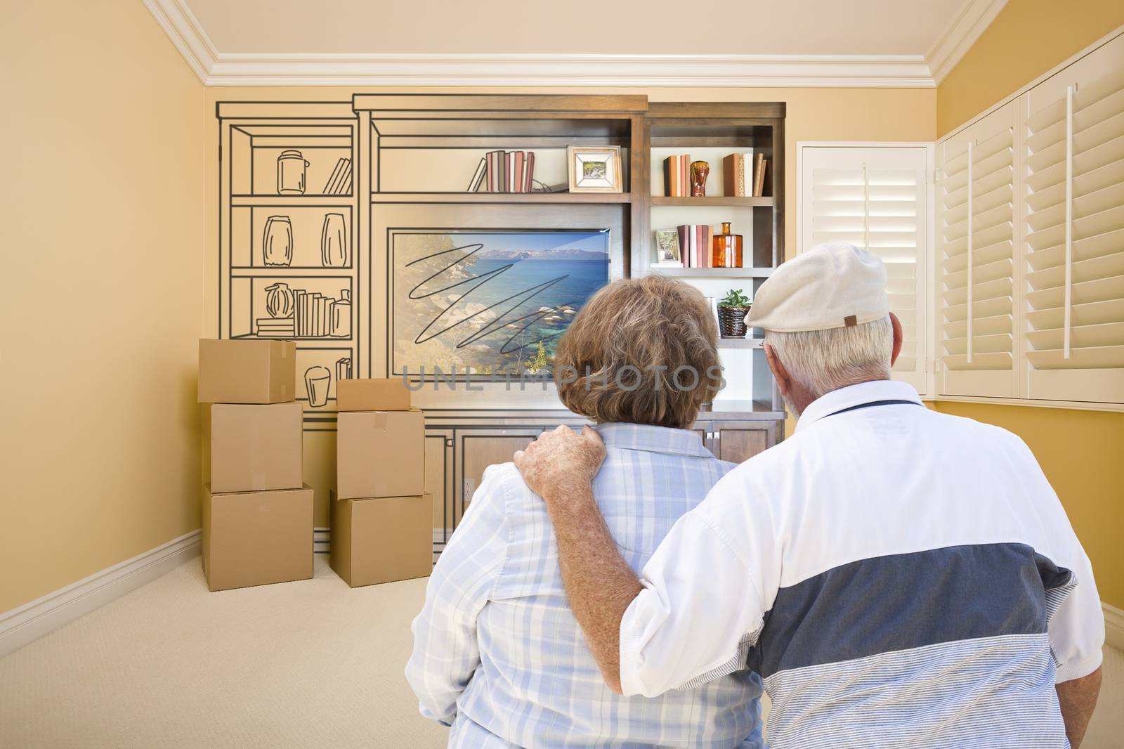 Senior Couple In Room With Moving Boxes Looking At Drawing of Entertainment Unit.