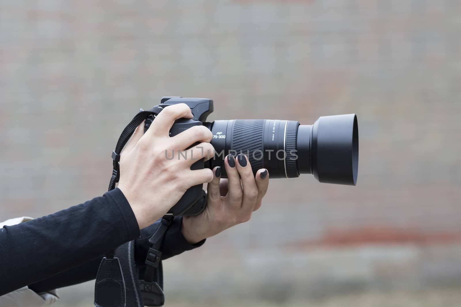 girl with beautiful manicure holds single-lens reflex camera