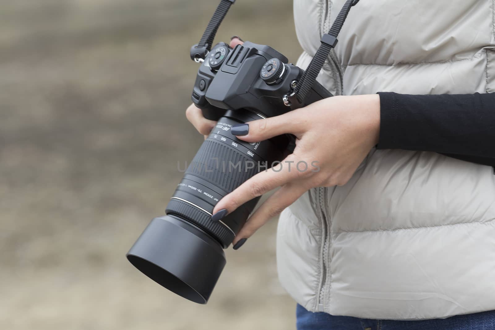 girl with beautiful manicure holds single-lens reflex camera
