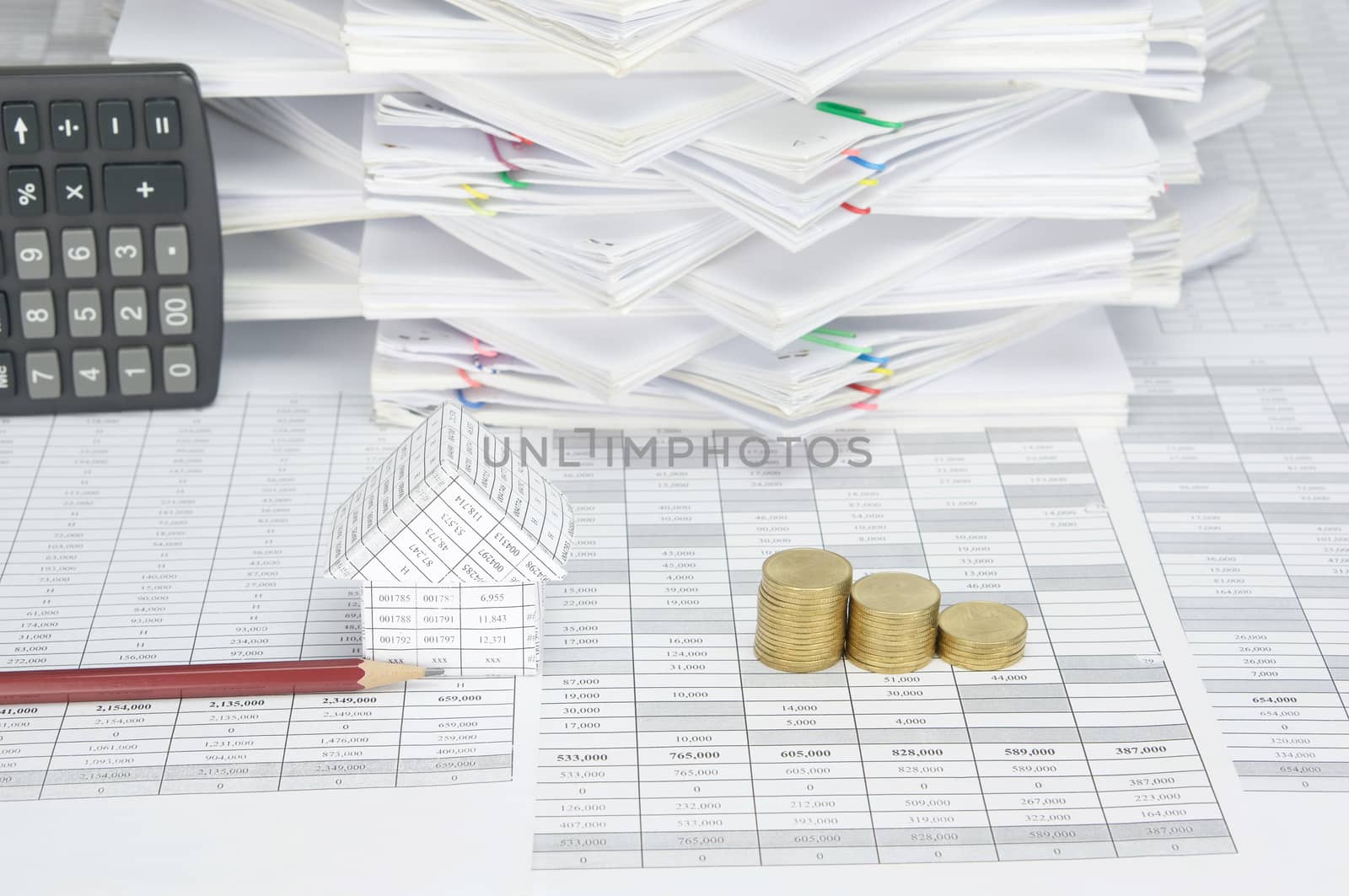 House and brown pencil  with step pile of gold coins on finance account have calculator place vertical and overload of paperwork with colorful paperclip as background.